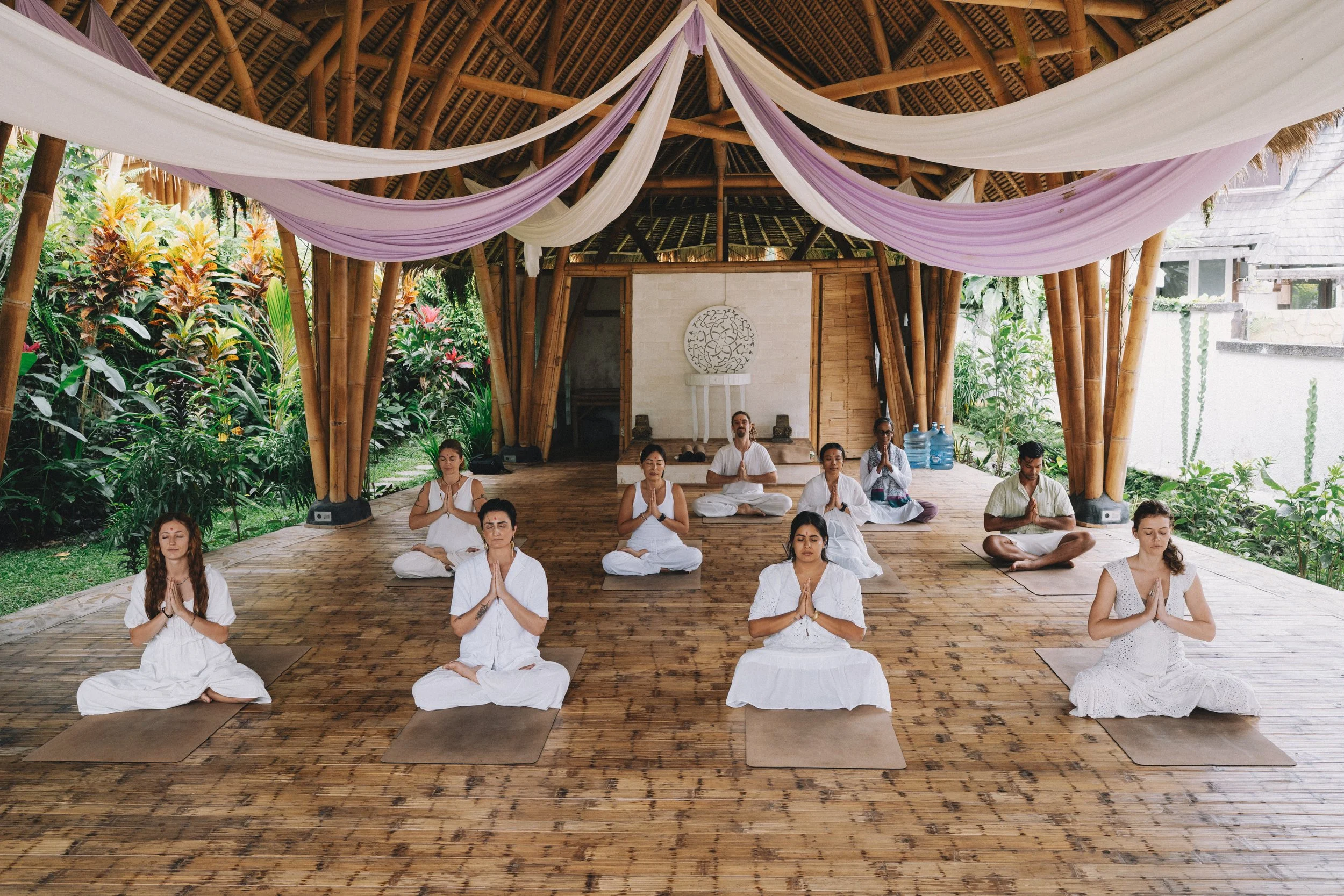 Yoga graduate dressed in white offering gratitude at the closing ceremony of SKY’s traditional Hatha Yoga Teacher Training in Bali