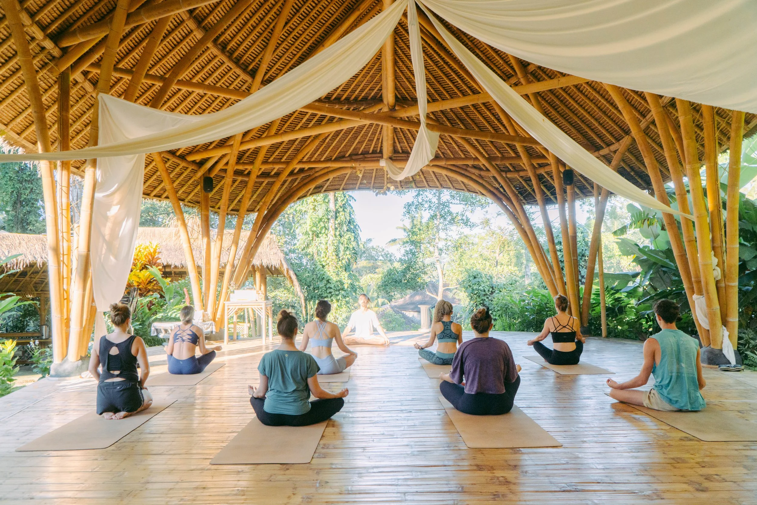 Yoga students meditating in a bamboo shala surrounded by nature at SKY Yoga and Meditation in Bali