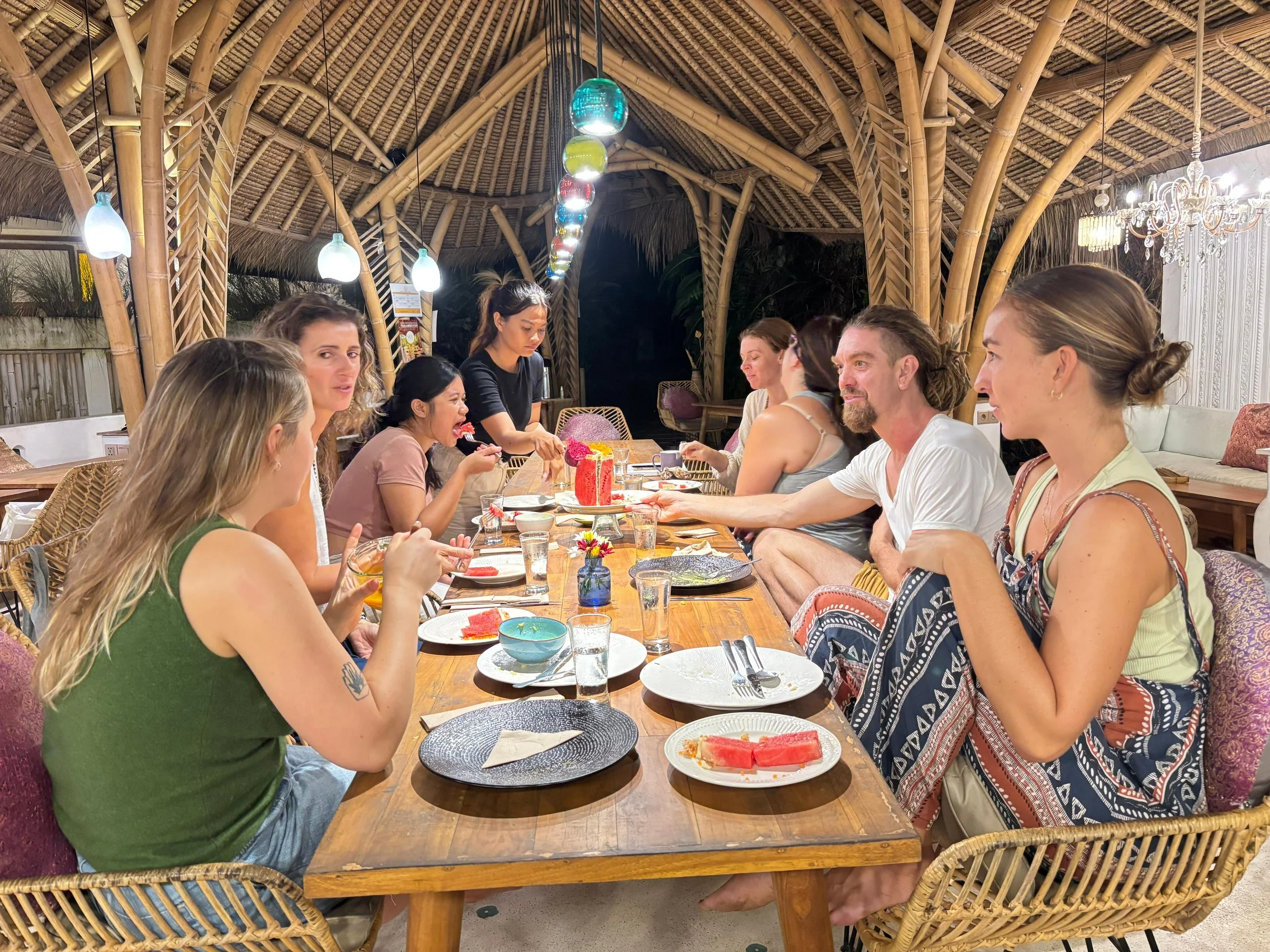 Yoga Teacher Training community sharing a plant-based communal dinner in the eco-village setting at SKY Yoga and Meditation in Bali