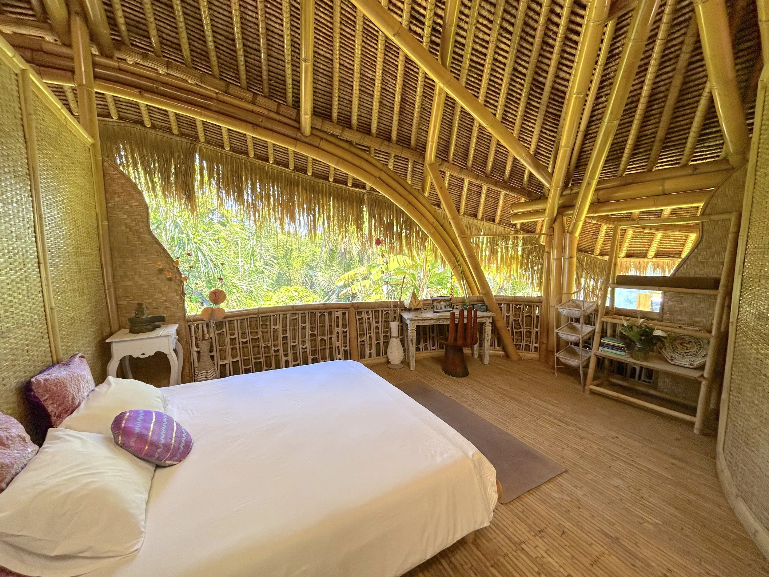Open bamboo double room at SKY Yoga and Meditation in Bali featuring a king bed, work desk, and stunning jungle views from an open-ceiling bamboo shala with a detached private bathroom.