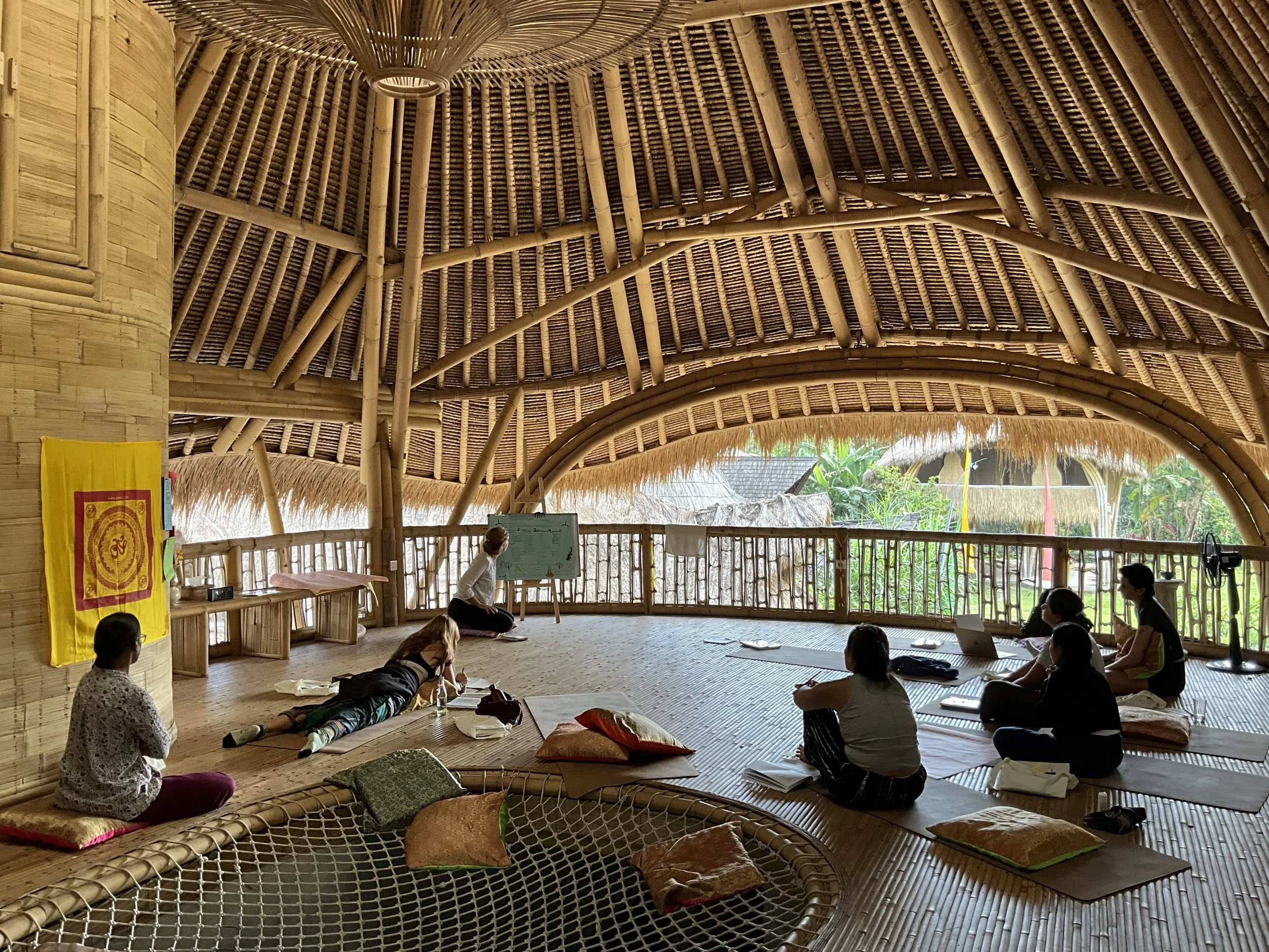 Students studying Hatha Yoga philosophy and anatomy theory inside the bamboo shala at SKY Yoga and Meditation Bali