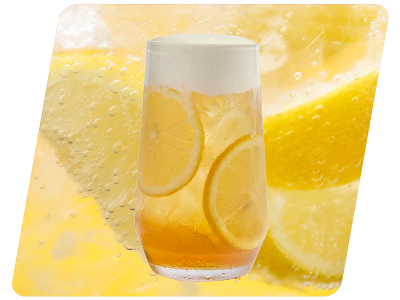 A glass of lemon soda with lemon slices and foam on top, against a background of lemon slices and bubbly soda.