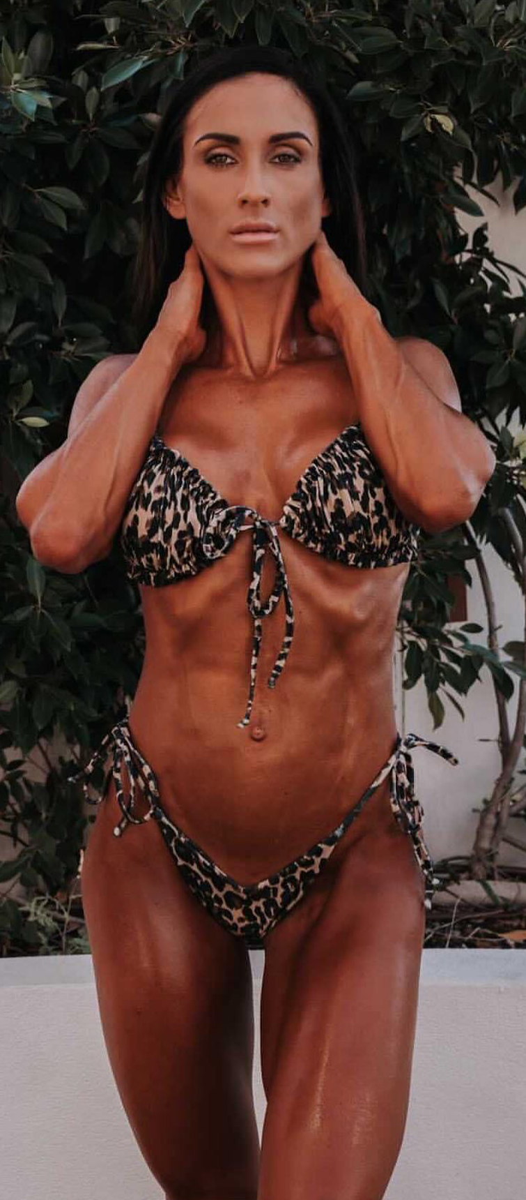 Jaydene wearing a leopard print bikini posing outdoors in front of greenery.