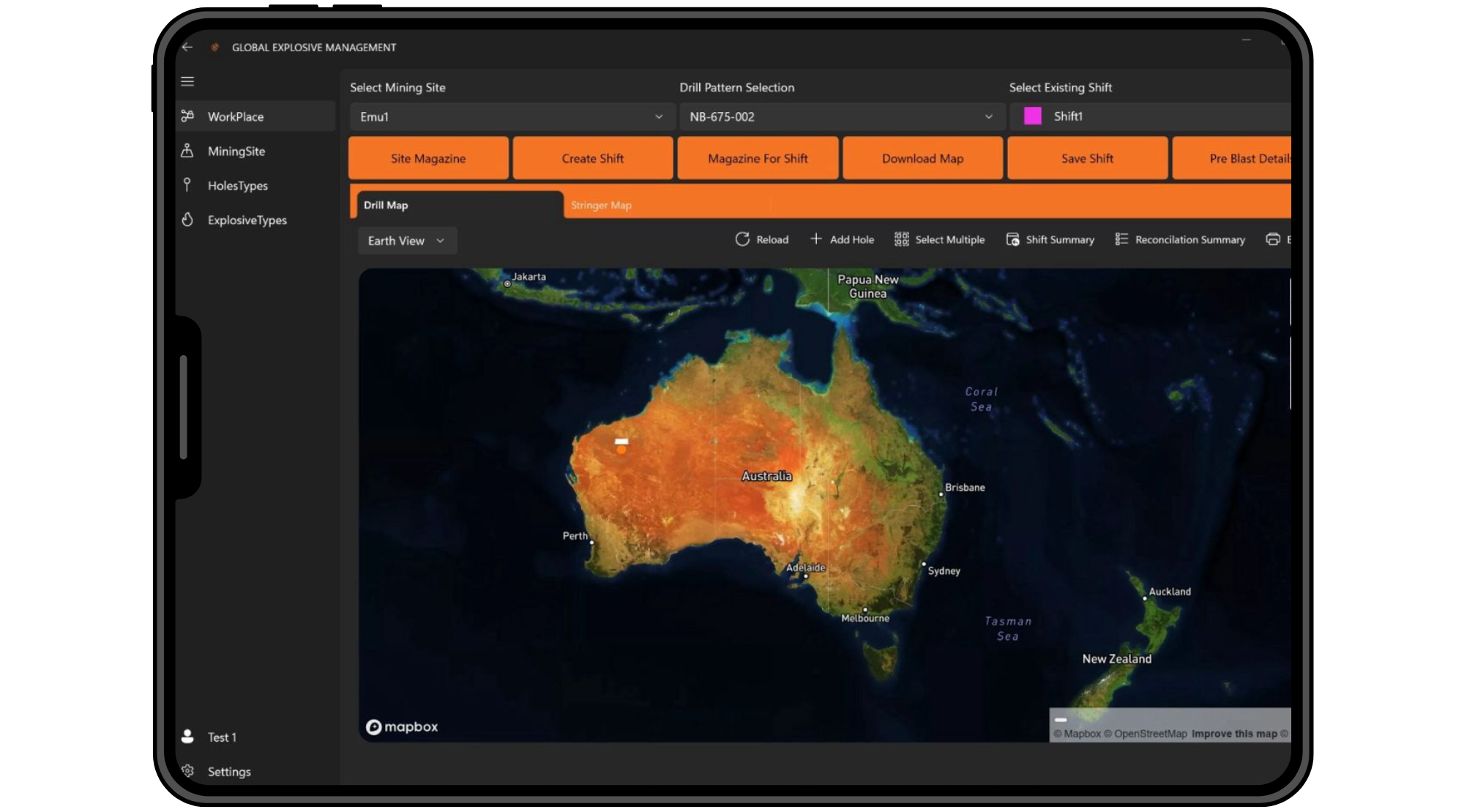 A tablet displaying a map of Australia with a heatmap overlay using colors from green to red, indicating different data levels, overlaid on the Earth's map. The user interface includes menu options on the left and orange buttons at the top labeled 'Site Magazine,' 'Create Shift,' 'Magazine For Shift,' 'Download Map,' 'Save Shift,' and 'Pre Blast Details.'