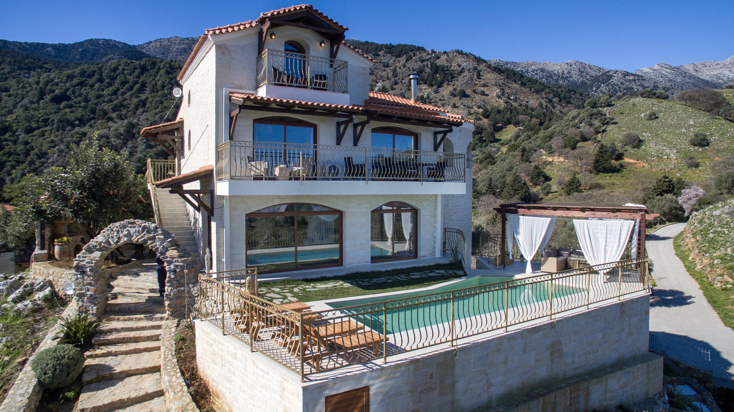 Stone villa with balconies and pool in mountainous landscape