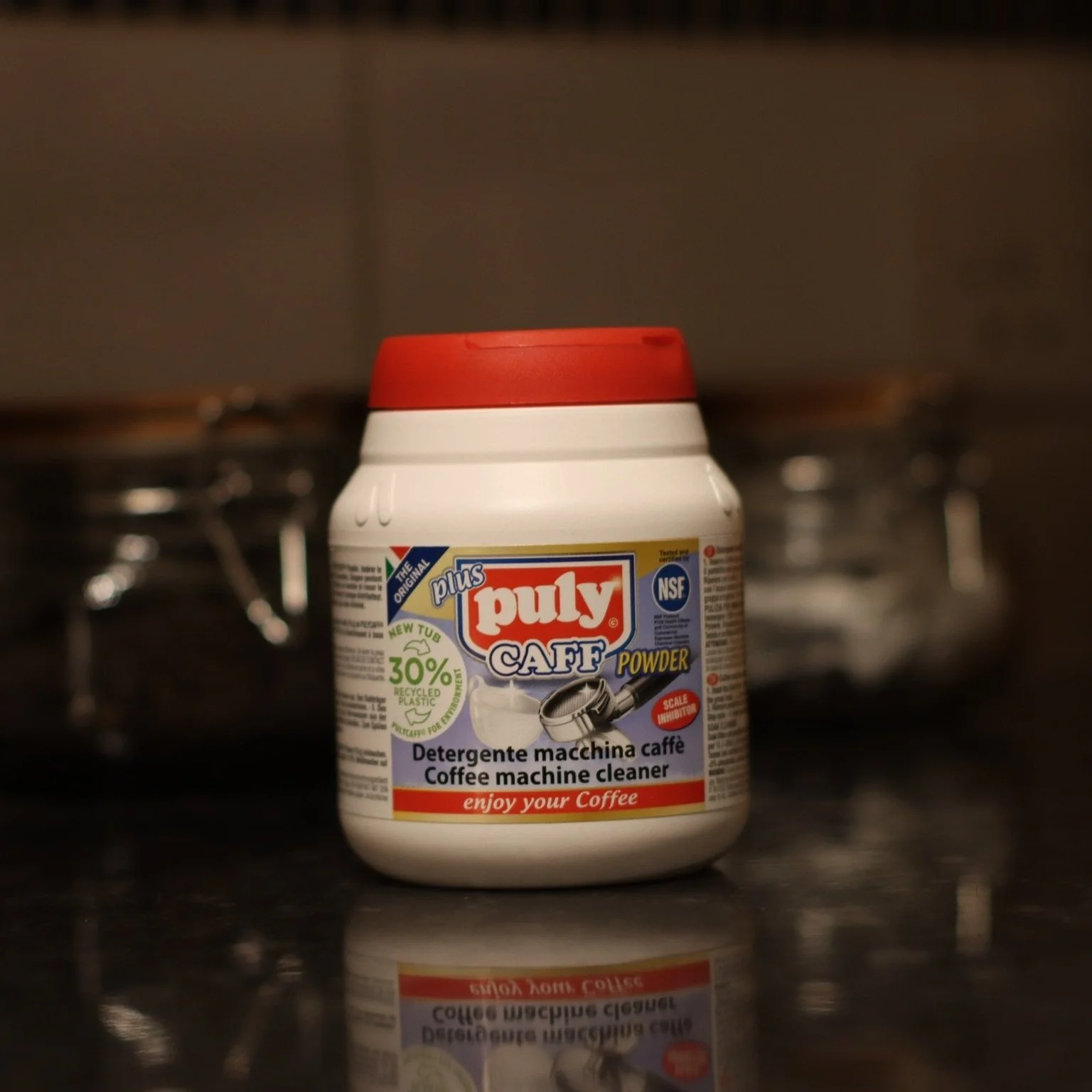 Tub of Puty Caff Espresso Cleaner Powder shown on black counter