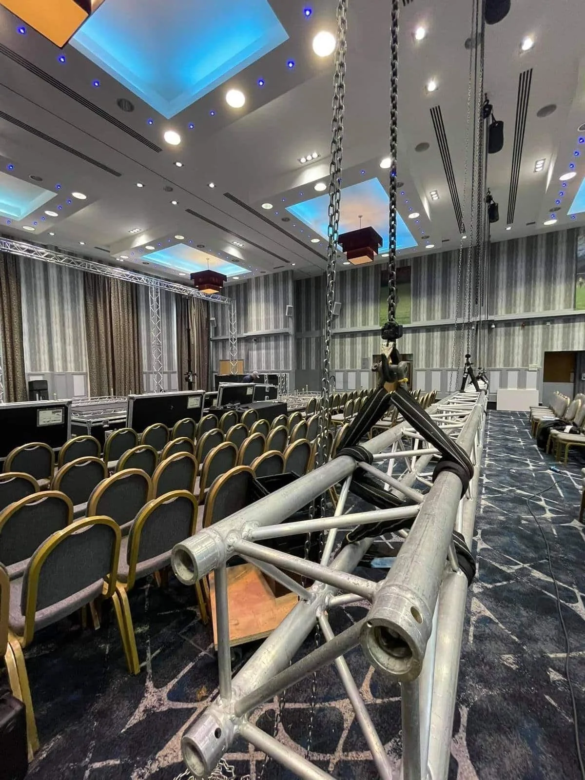 An AV equipment supplier installing truss to mount a projector hire in a hotel ballroom