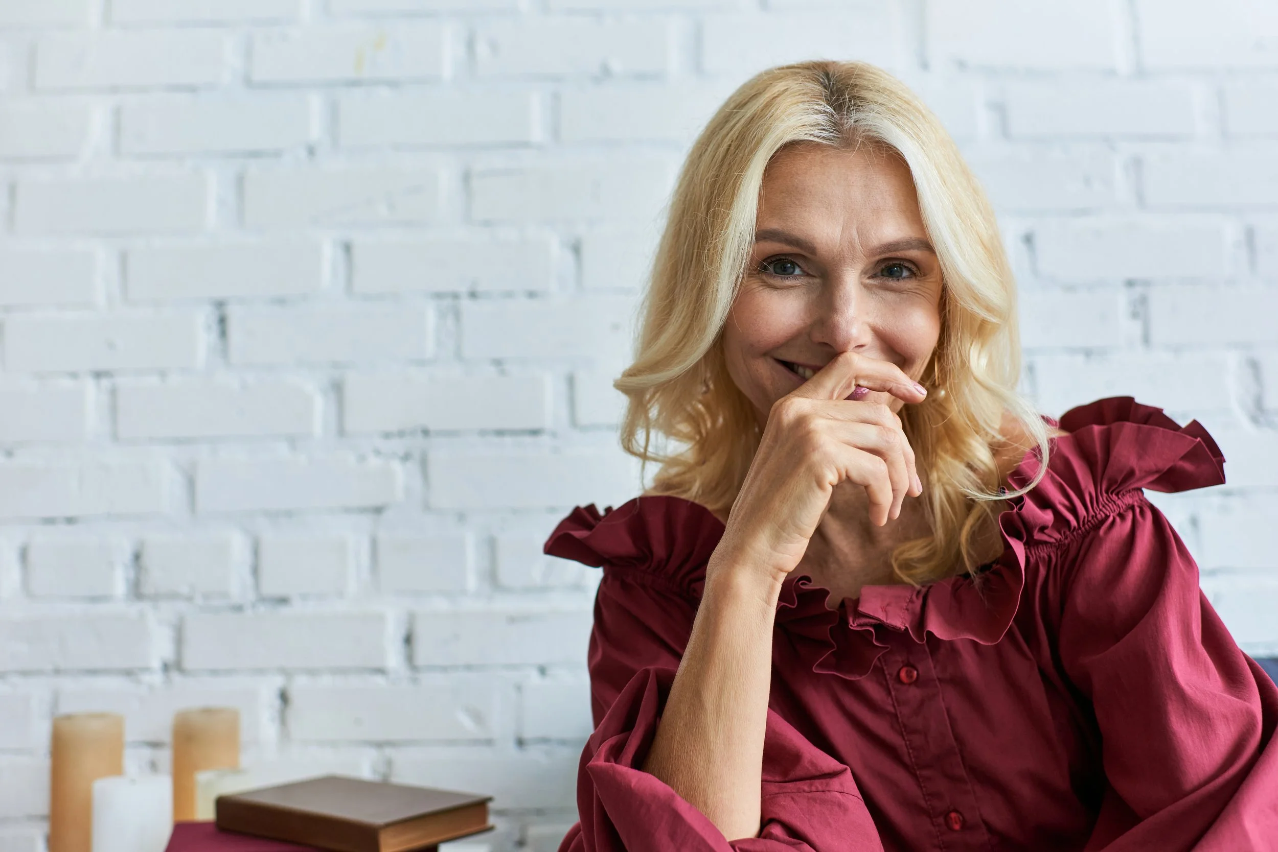 smiling-woman-poses-in-front-of-white-brick-wall-2026-01-06-00-22-15-utc.jpg