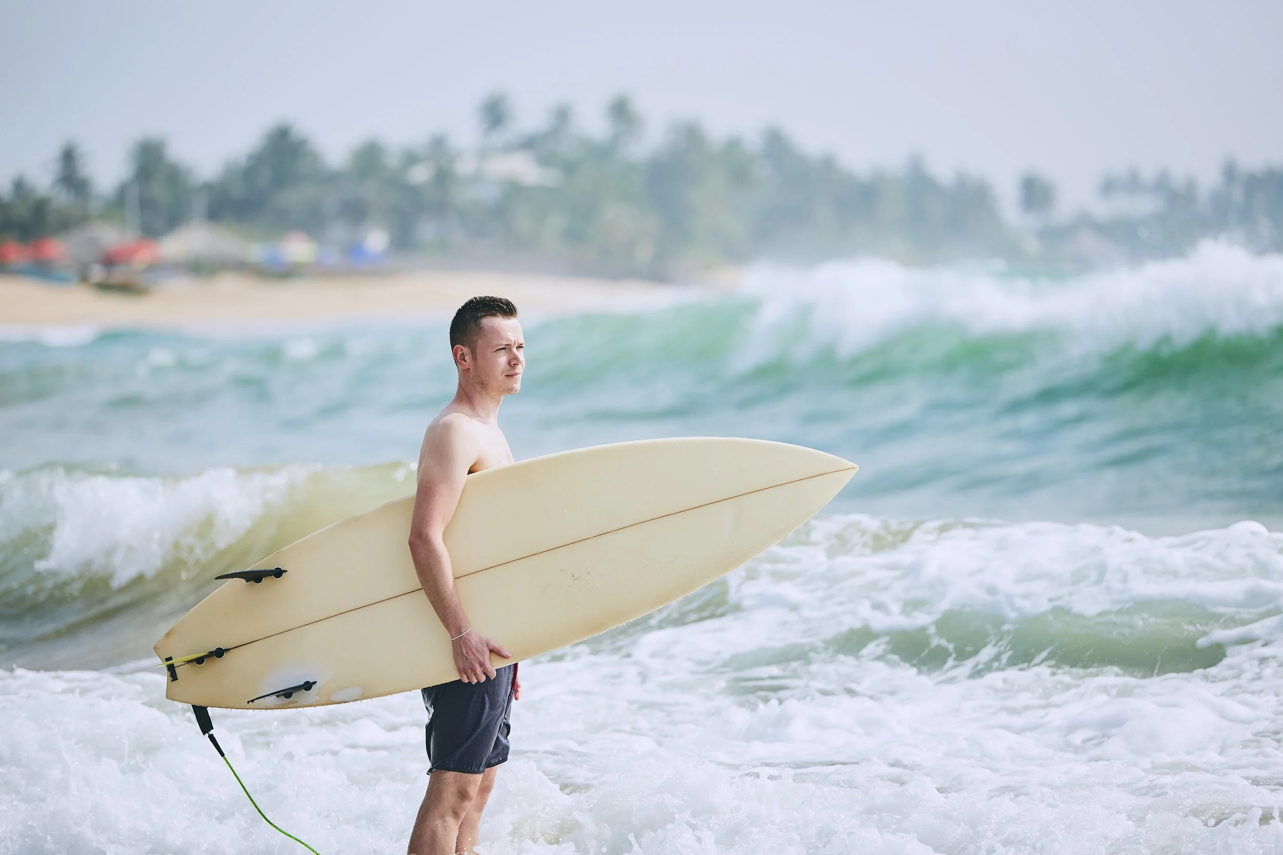 surfer-standing-with-surfboard-on-tropical-beach-2026-03-18-17-45-59-utc.jpg