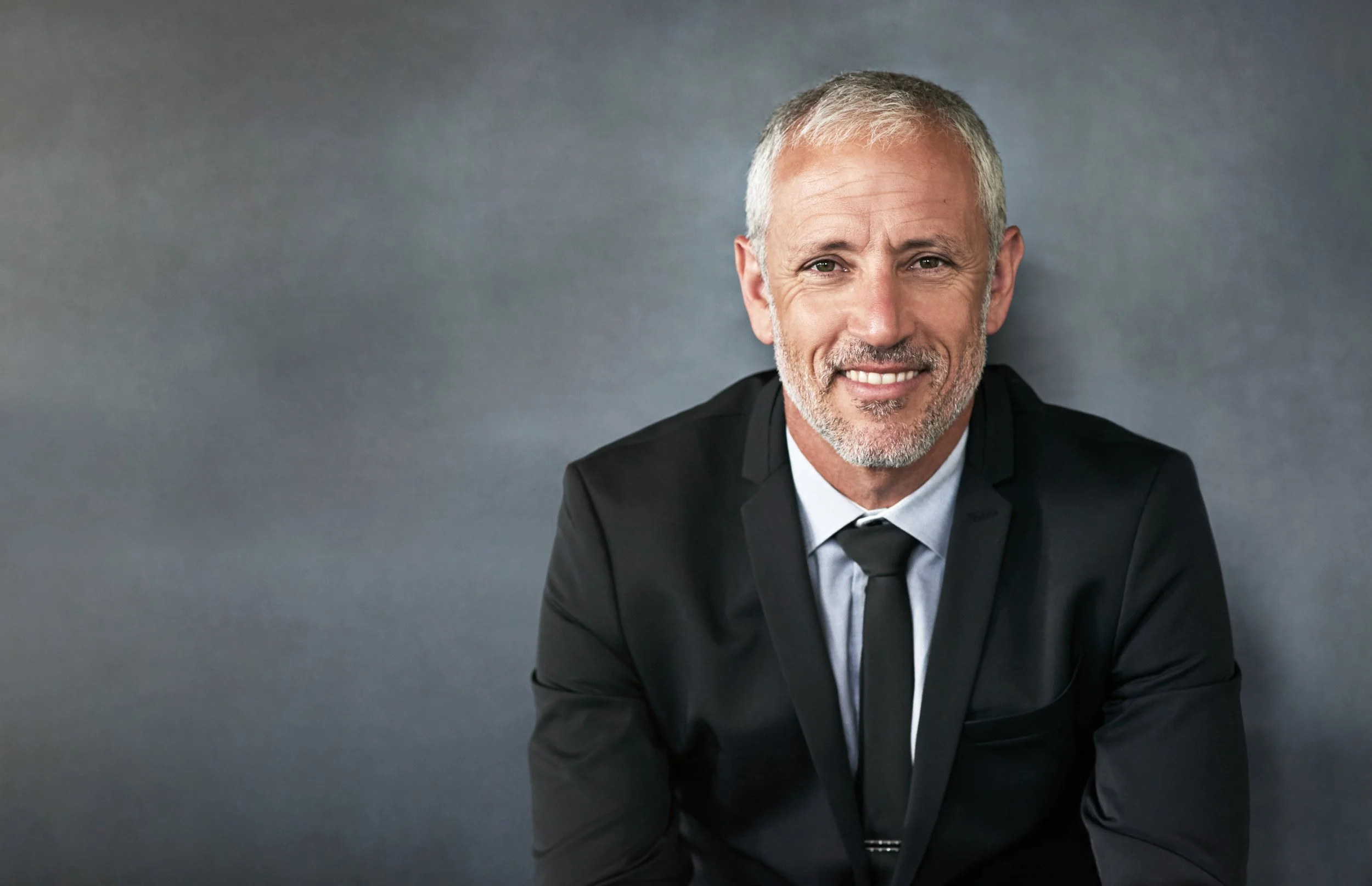 smiling-man-in-suit-against-grey-background-2026-01-09-09-35-05-utc.jpg