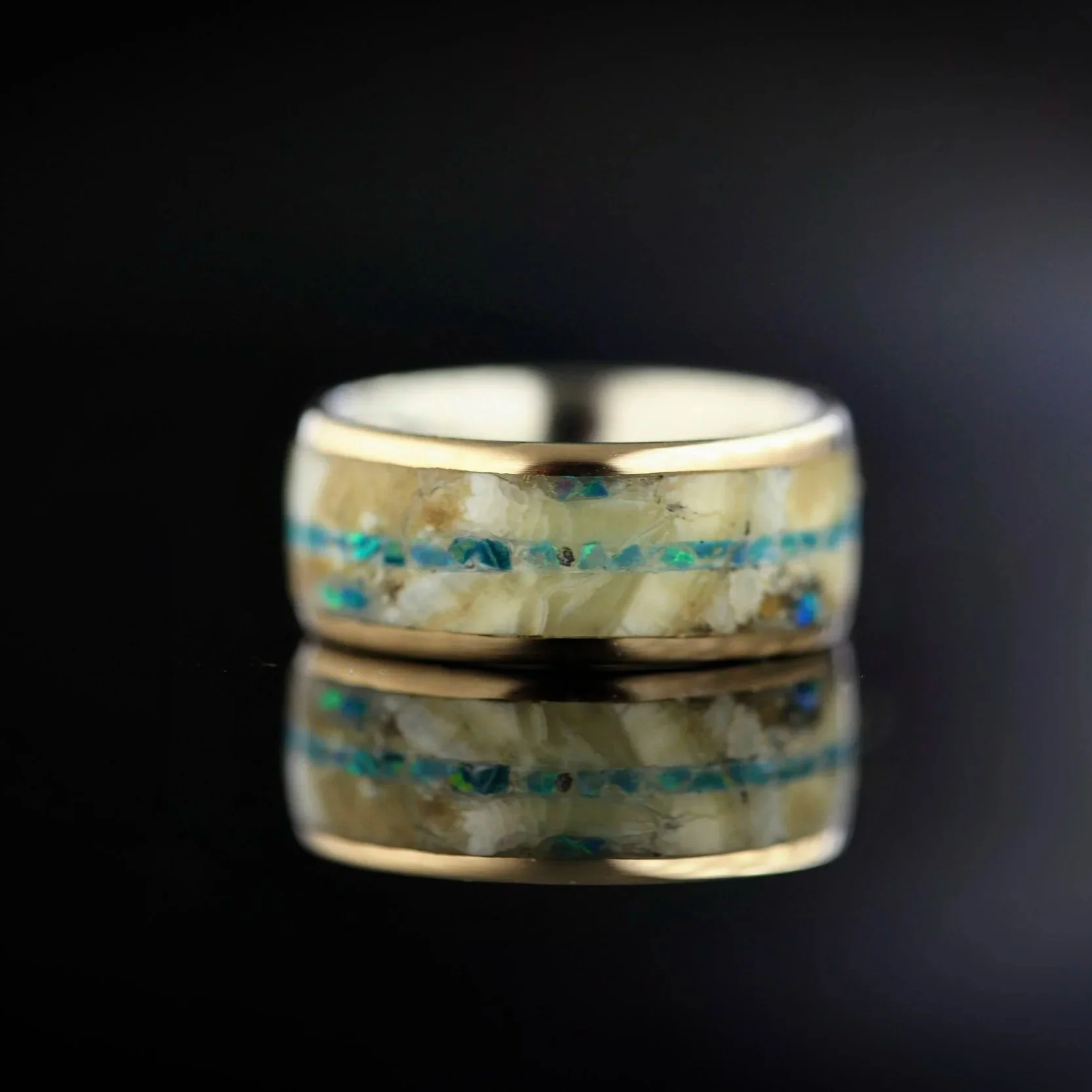 detalje af håndlavet ring med mammutkindtand, 14 kt guld og grønne opaler