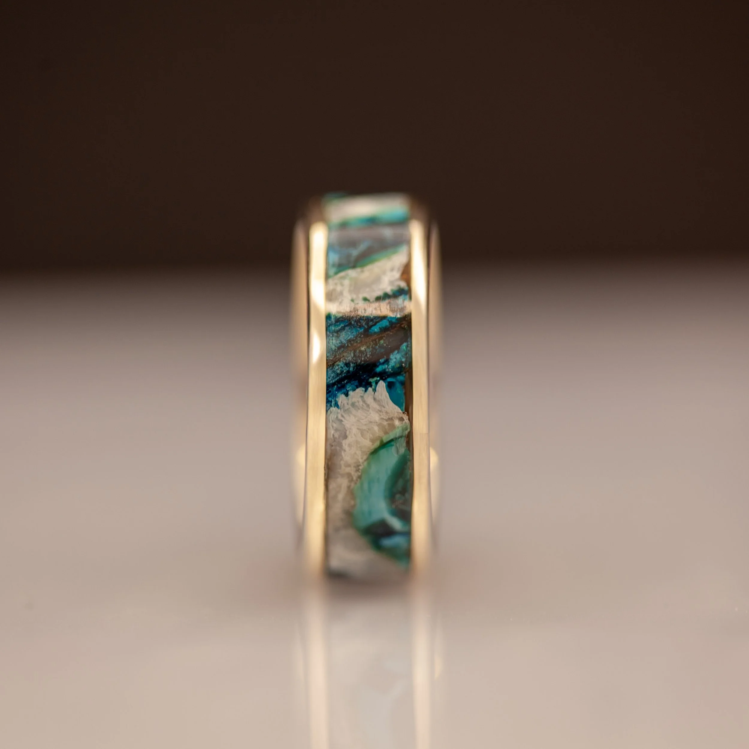 detalje af grøn mammutkindtand i håndlavet ring med 14 kt guld