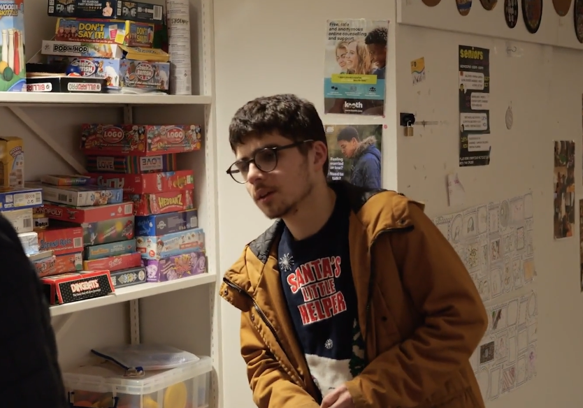 A young man standing in front of shelves with board games