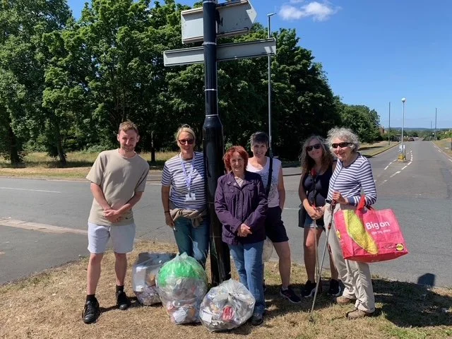 Six members of the Stockwood Wombles team standing outdoors next to a street sign, following a community litter-pick activity.