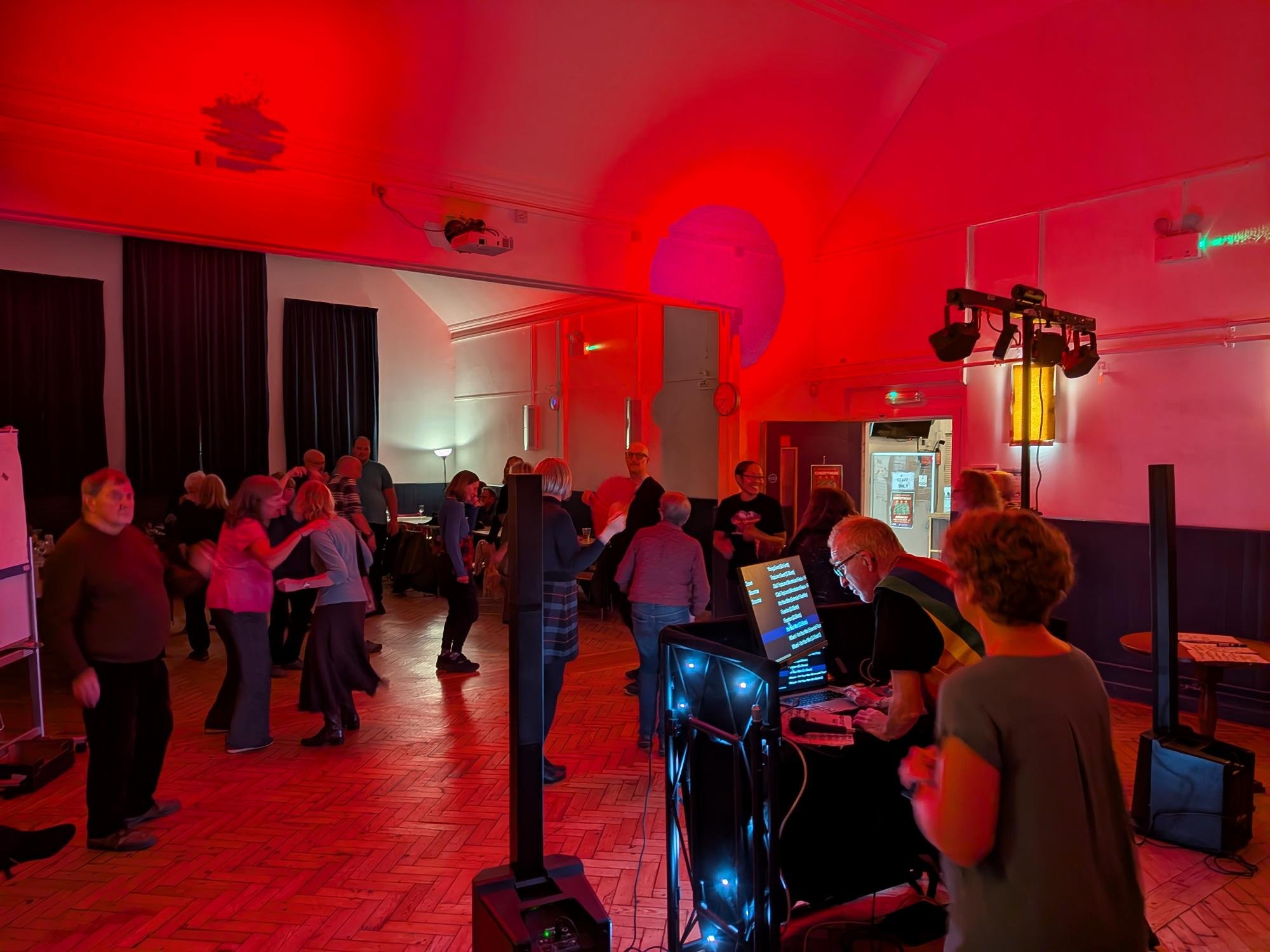 People dancing in a community disco, bathed in coloured lights