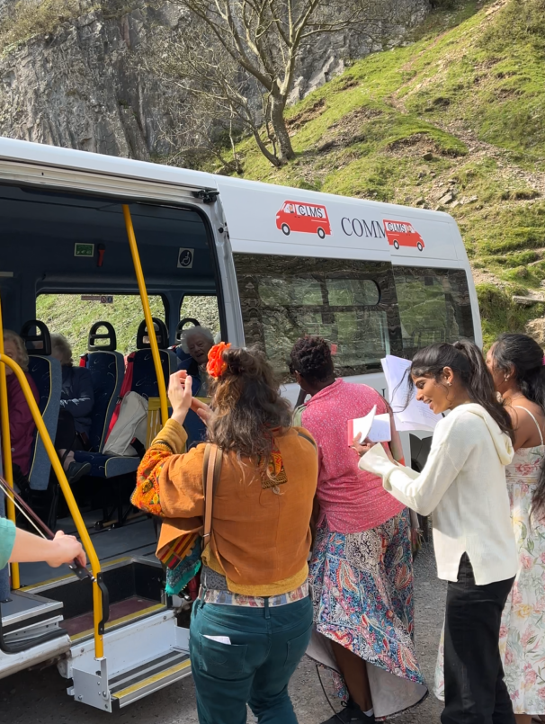 A group of people singing around and in a community minibus