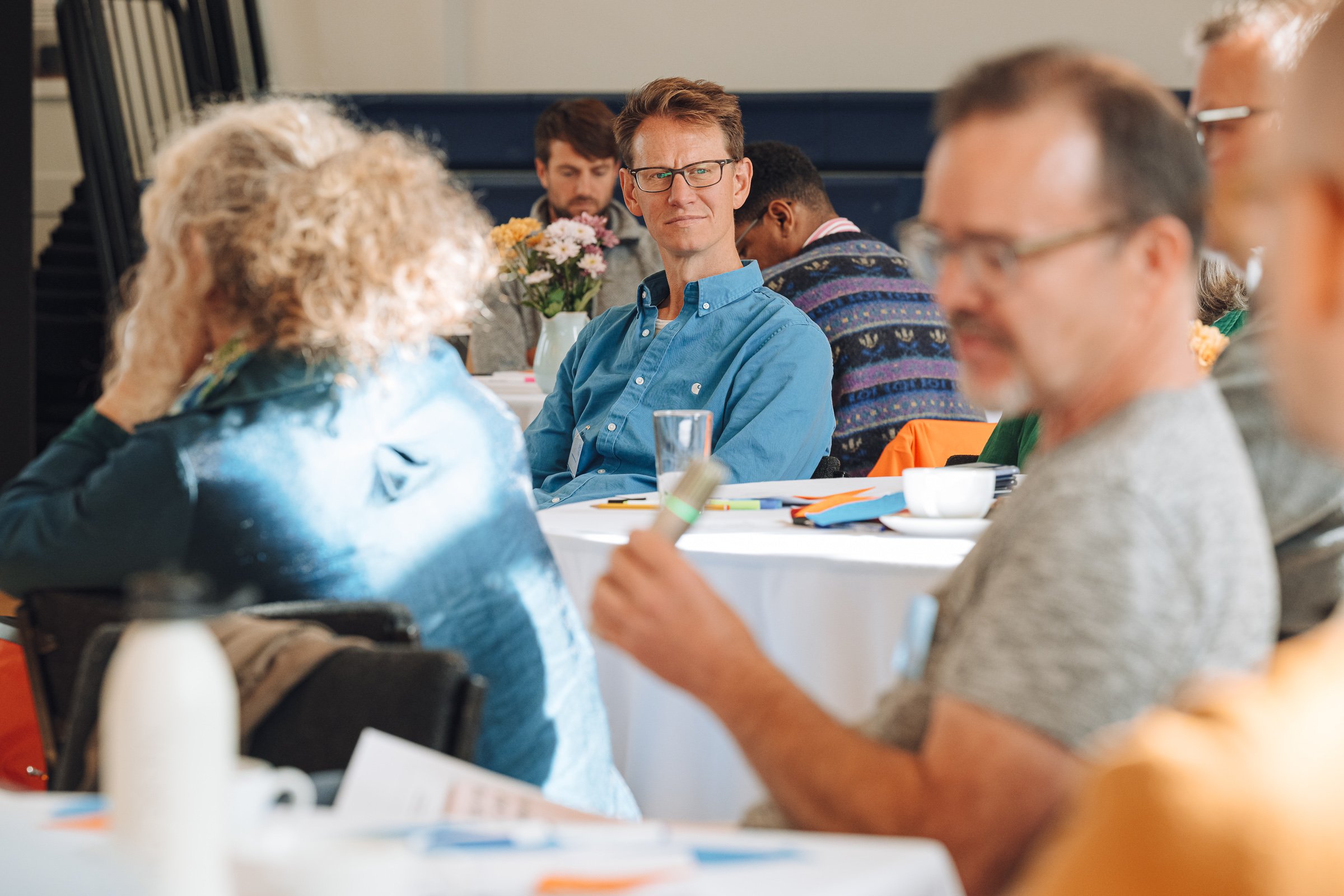 Group of people sitting at round tables, attending the Enablers' workshop.
