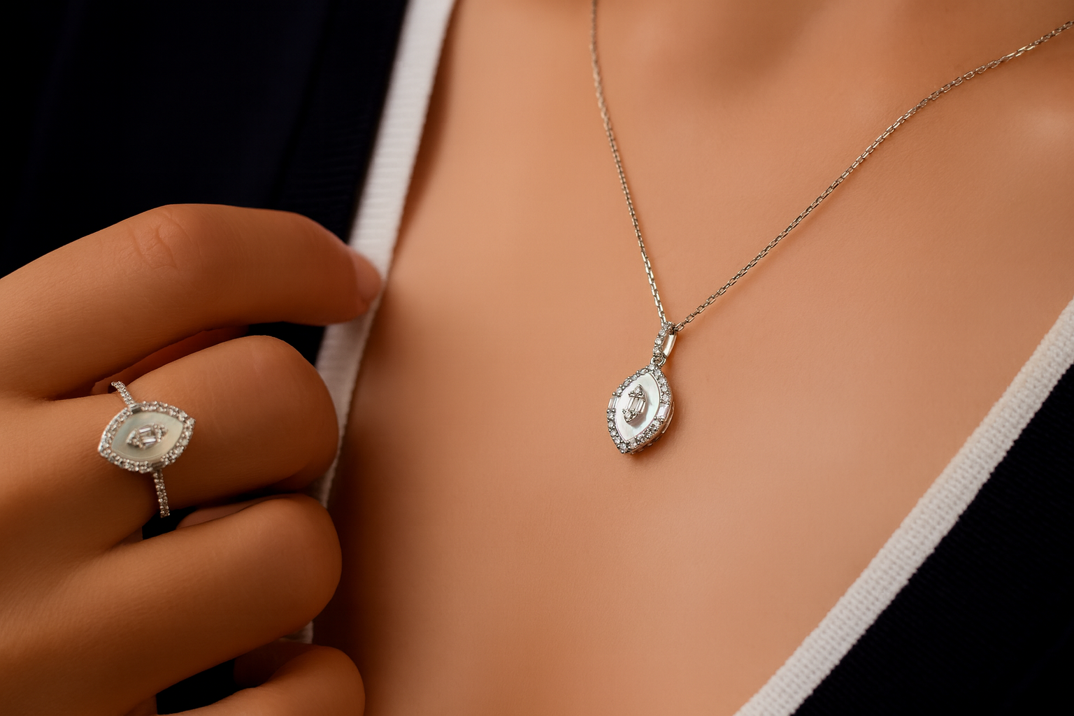Close-up of a woman wearing a necklace with a pendant, a matching ring, and a black and white jacket.