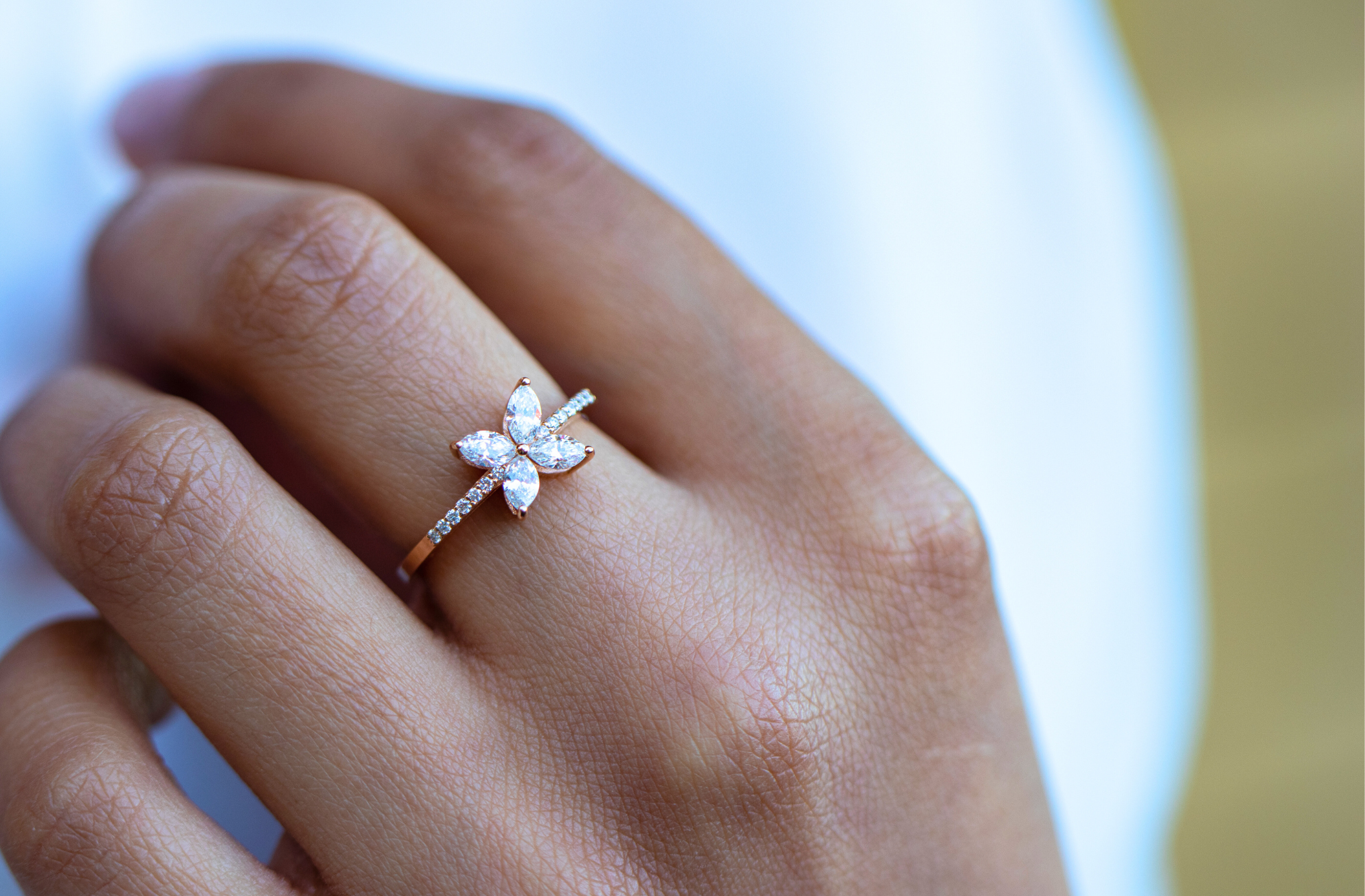 Close-up of a hand wearing a gold ring with a butterfly-shaped cluster of diamonds on the ring finger.