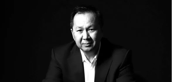 Black and white portrait of a man in a suit looking at the camera with a neutral expression.