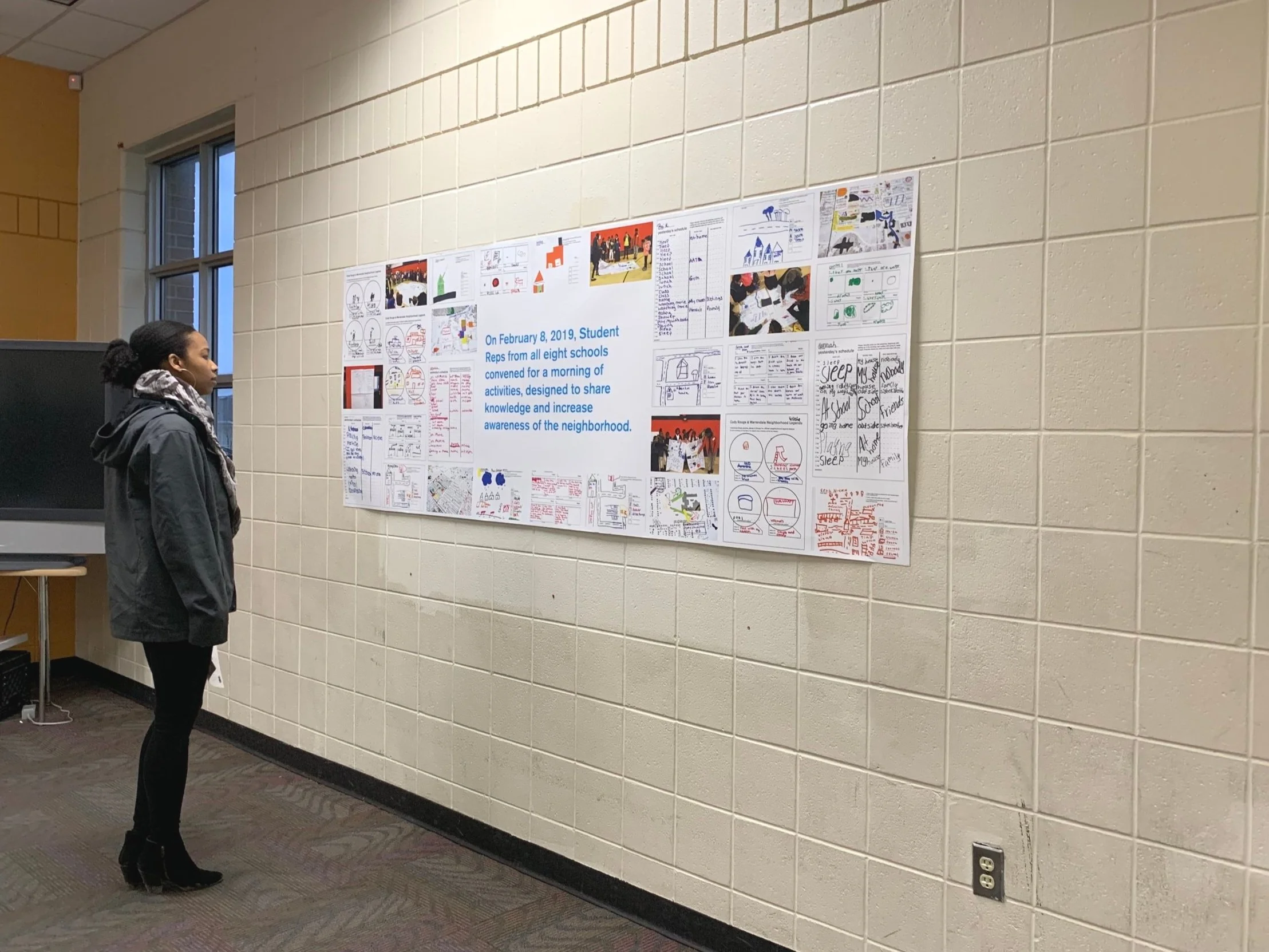 Black teenage girl stands in front of poster featuring project highlights.
