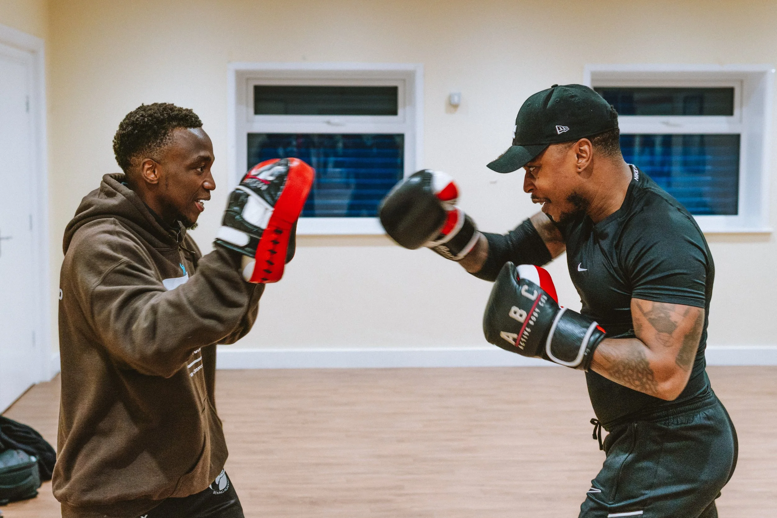 Two men wearing boxing gloves practicing sparring in a boxing gym.