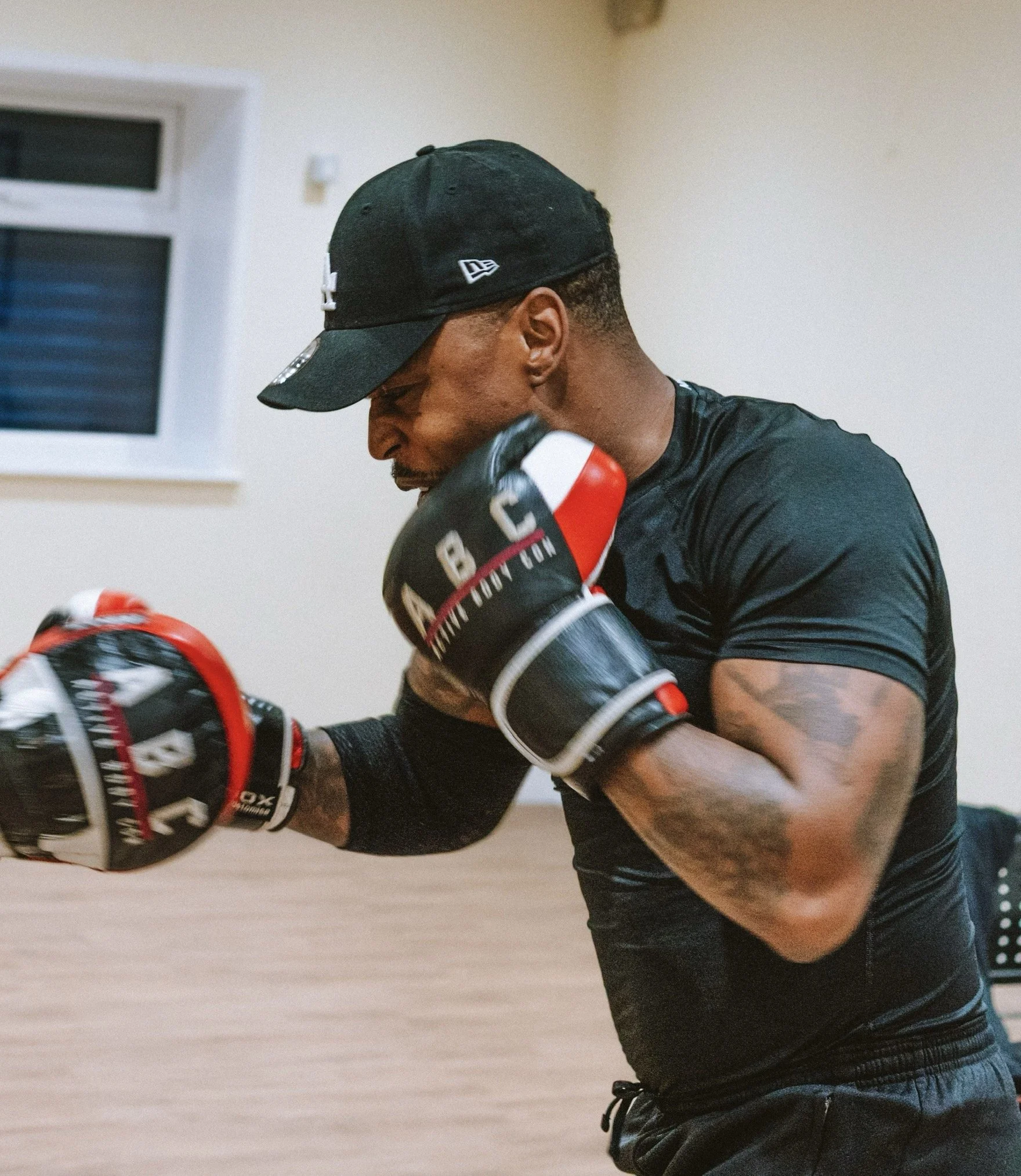A man in black athletic gear punching a boxing bag in a training session.