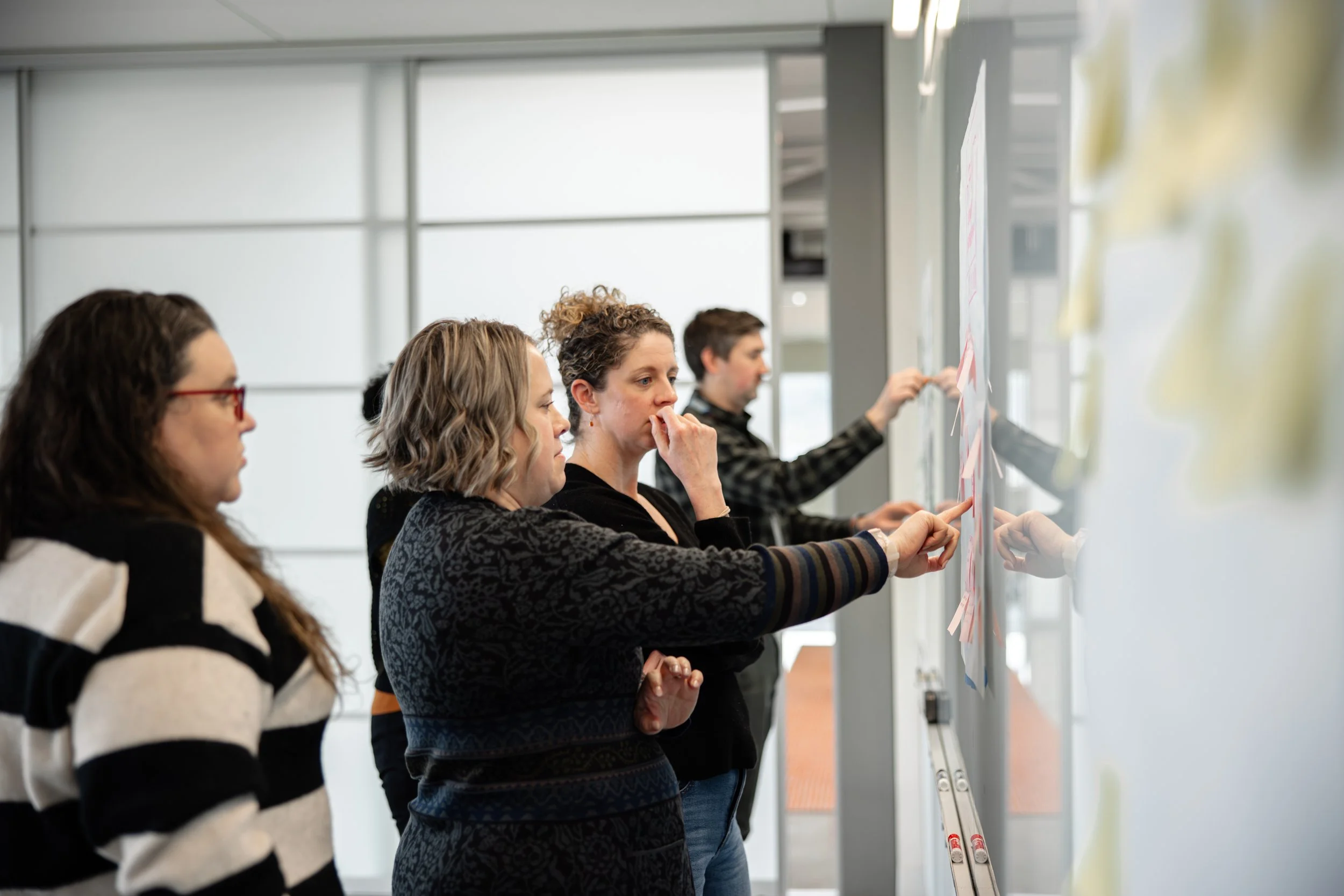 A group of people discuss sticky notes and a white board as they go through management skills training