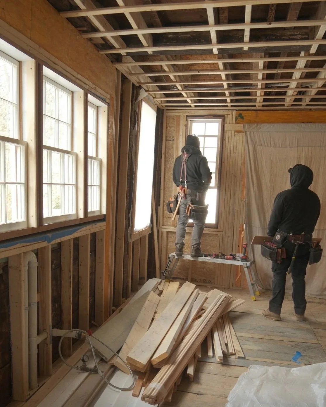 A person measuring and working on a wooden frame in a woodworking shop.