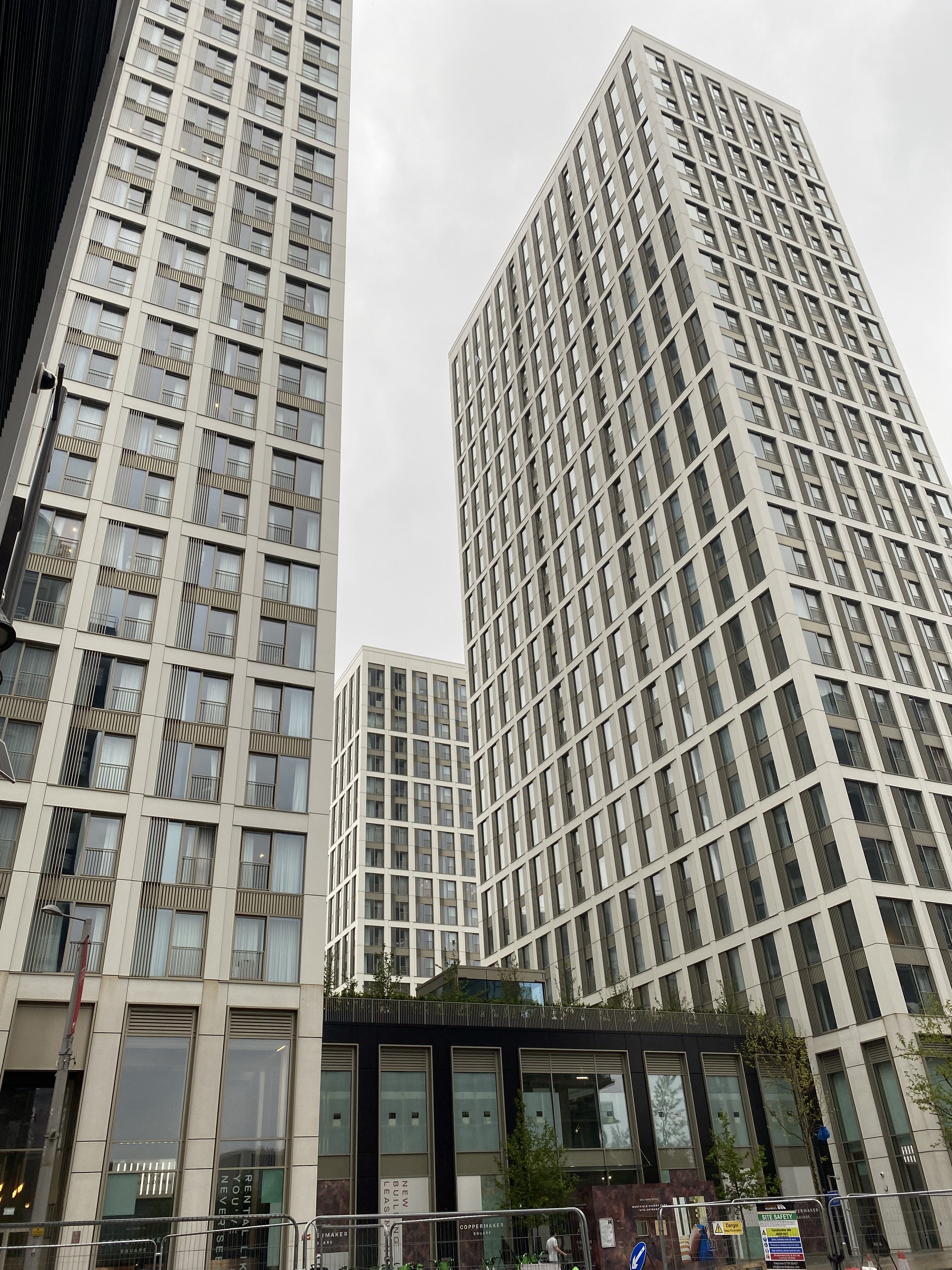 Tall modern skyscrapers with large windows and a black lower floor, viewed from street level in an urban setting.