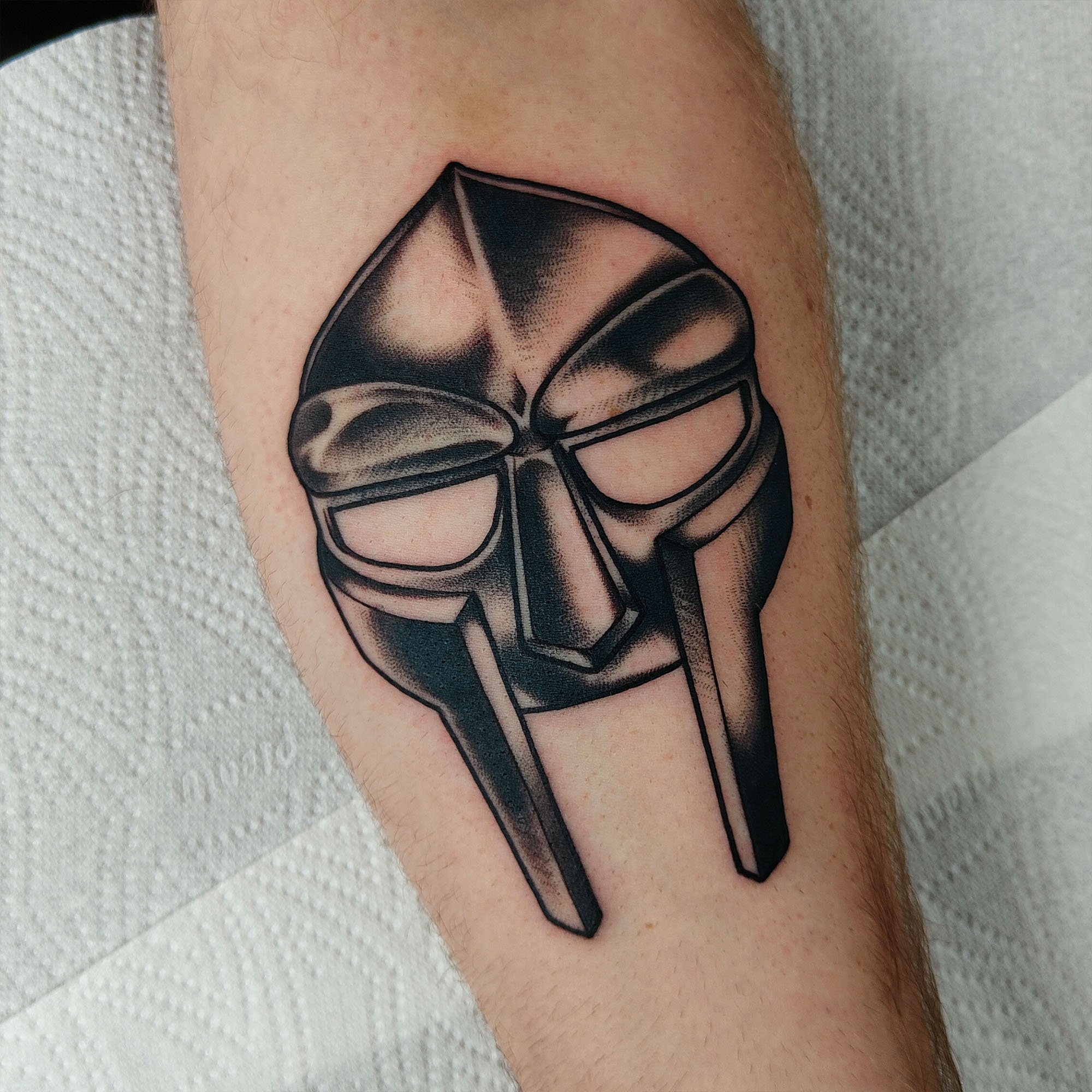 Tattoo of a stylized mask on skin.