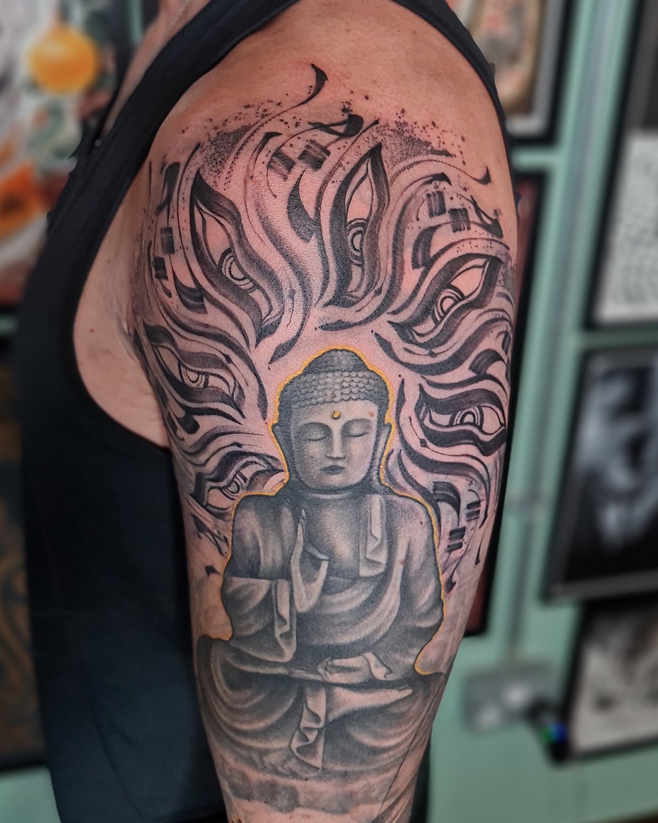 Buddha tattoo with flowing patterns on upper arm