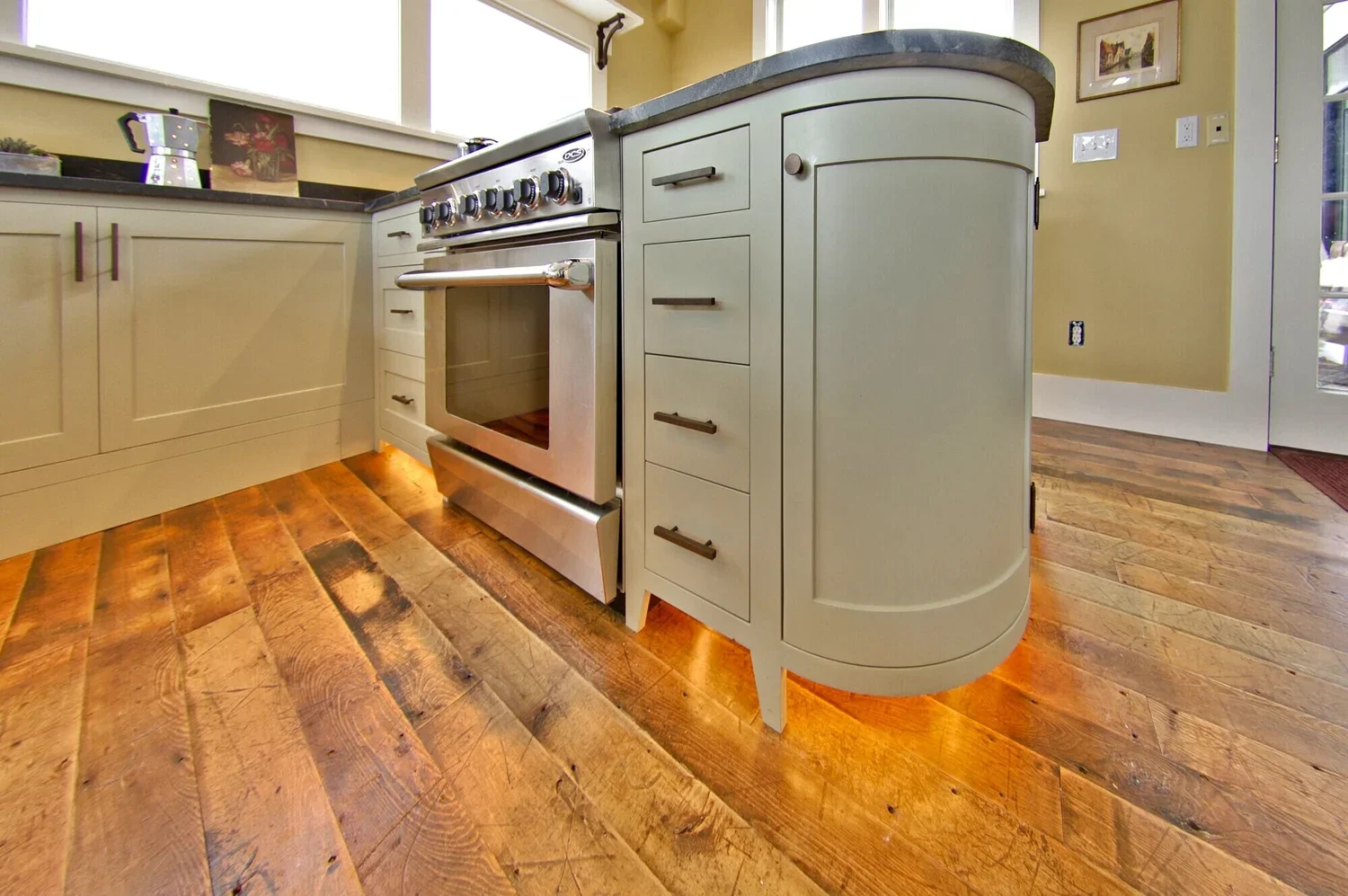 Kitchen painted with a light green curved cabinet and a stainless steel stove.