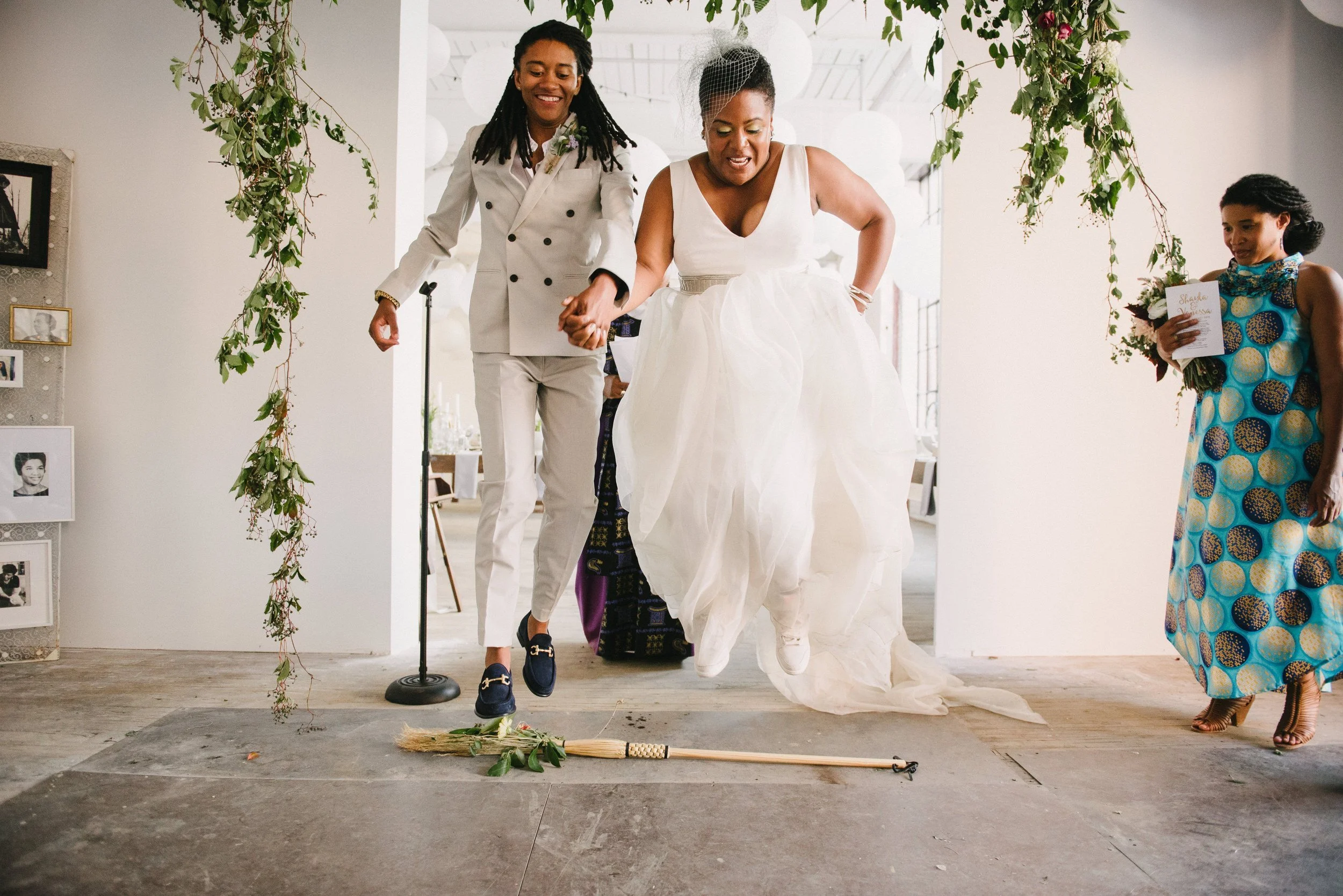 COUPLE JUMPING THE BROOM ON THEIR WEDDING DAY