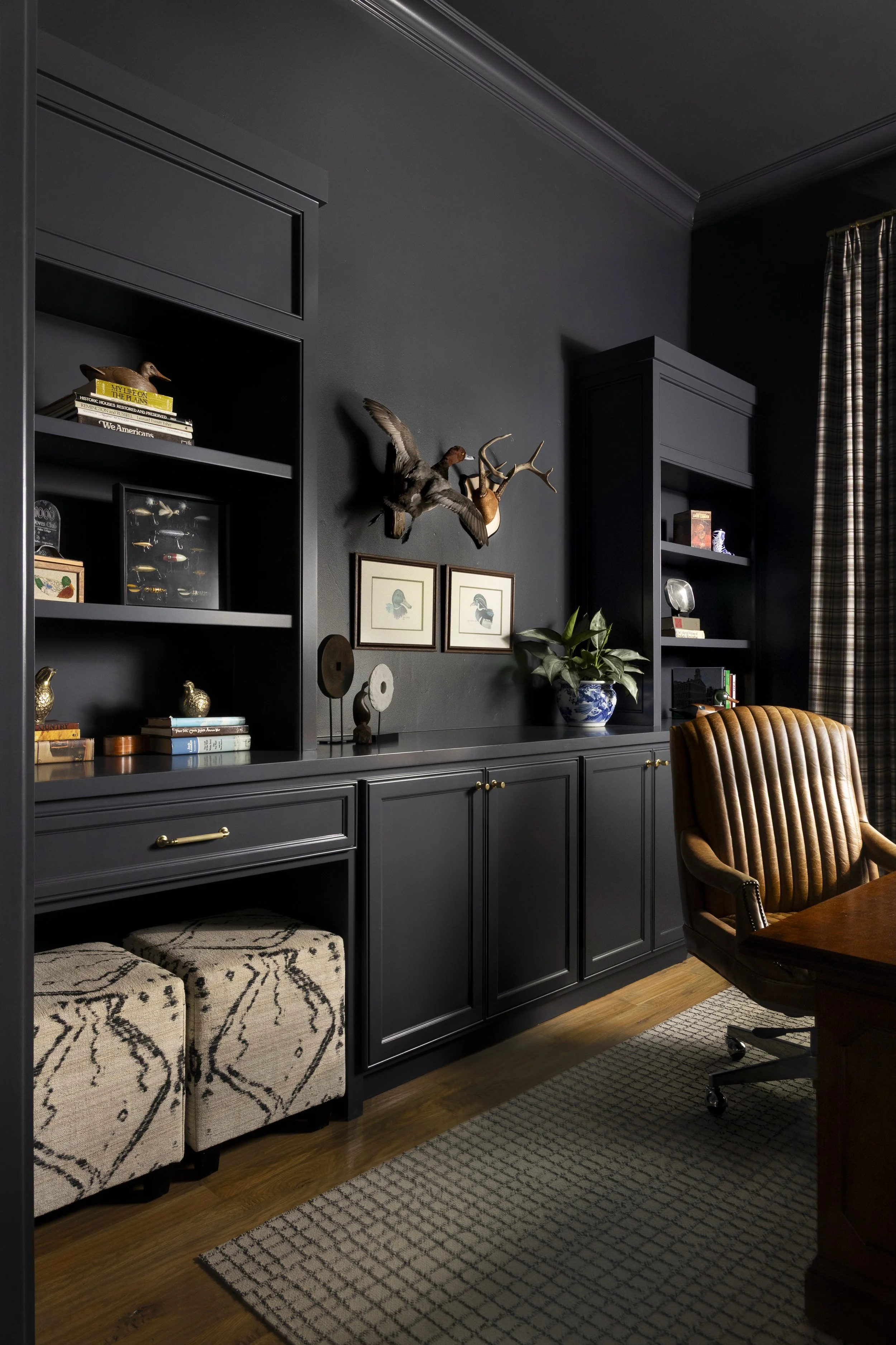 Floor-to-ceiling built-ins and moody finishes create a sophisticated workspace in a Dallas-Fort Worth area home.