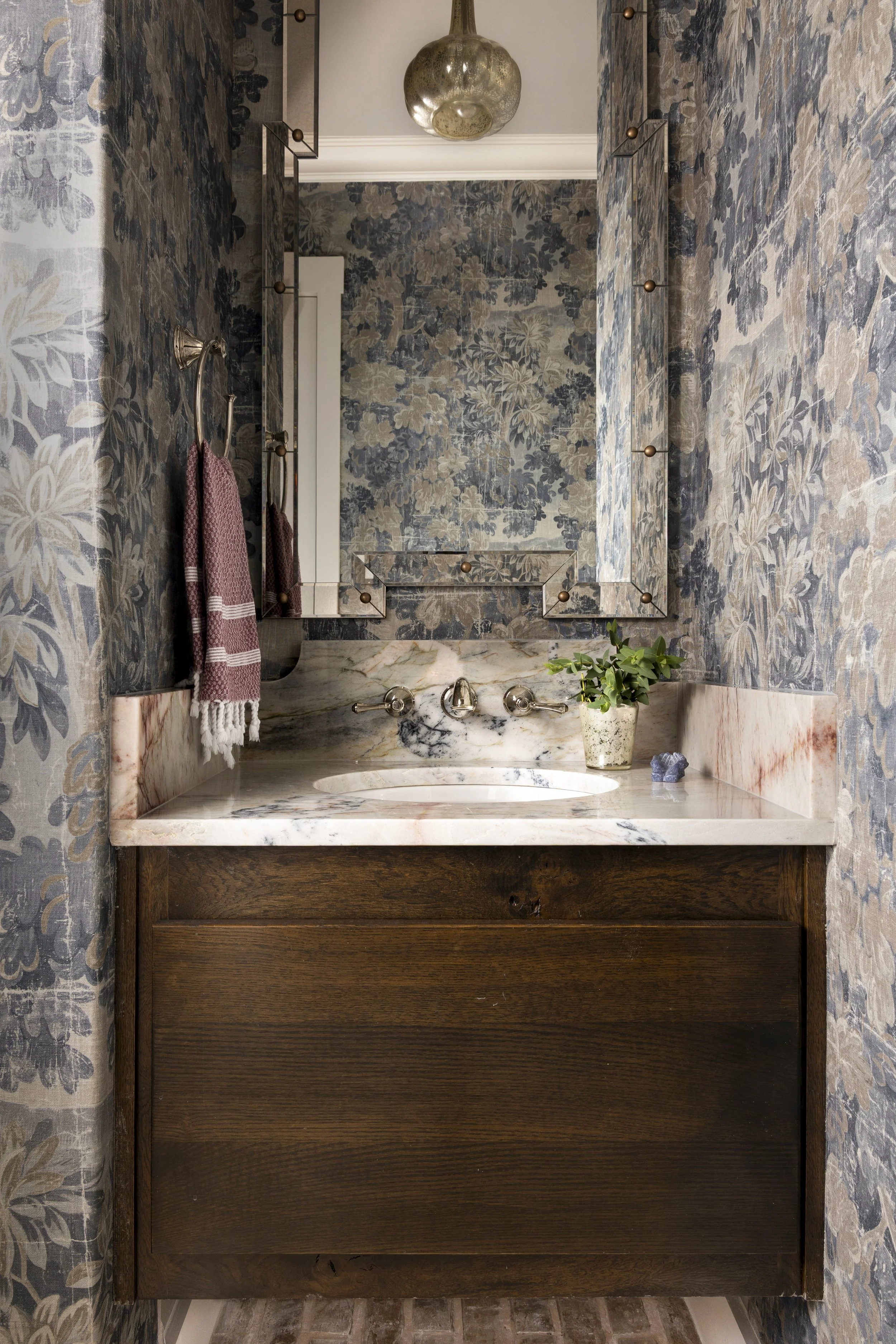 Custom millwork, natural stone, and layered materials elevate this powder room in a Dallas-Fort Worth area home.