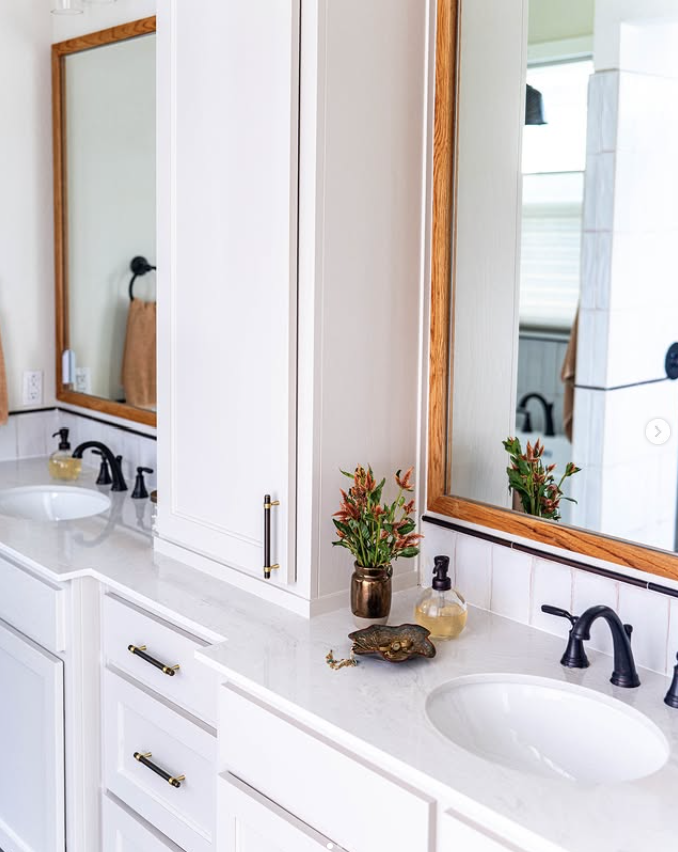 primary bathroom design with double vanity, white cabinetry, oil rubbed bronze fixtures, and warm wood mirrors in Argyle Texas