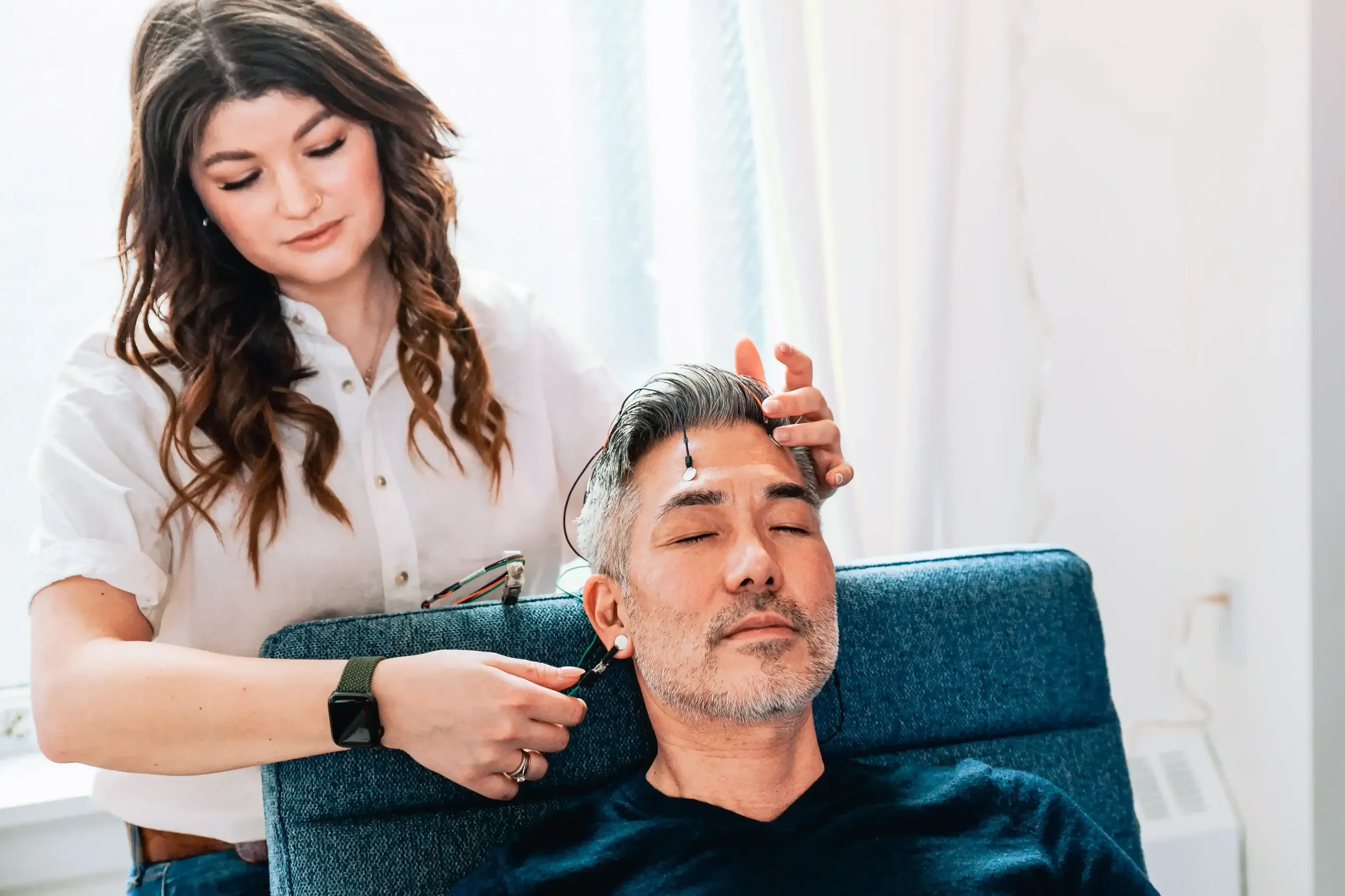 Man receives LENS neurofeedback with sensors attached to his forehead and ears