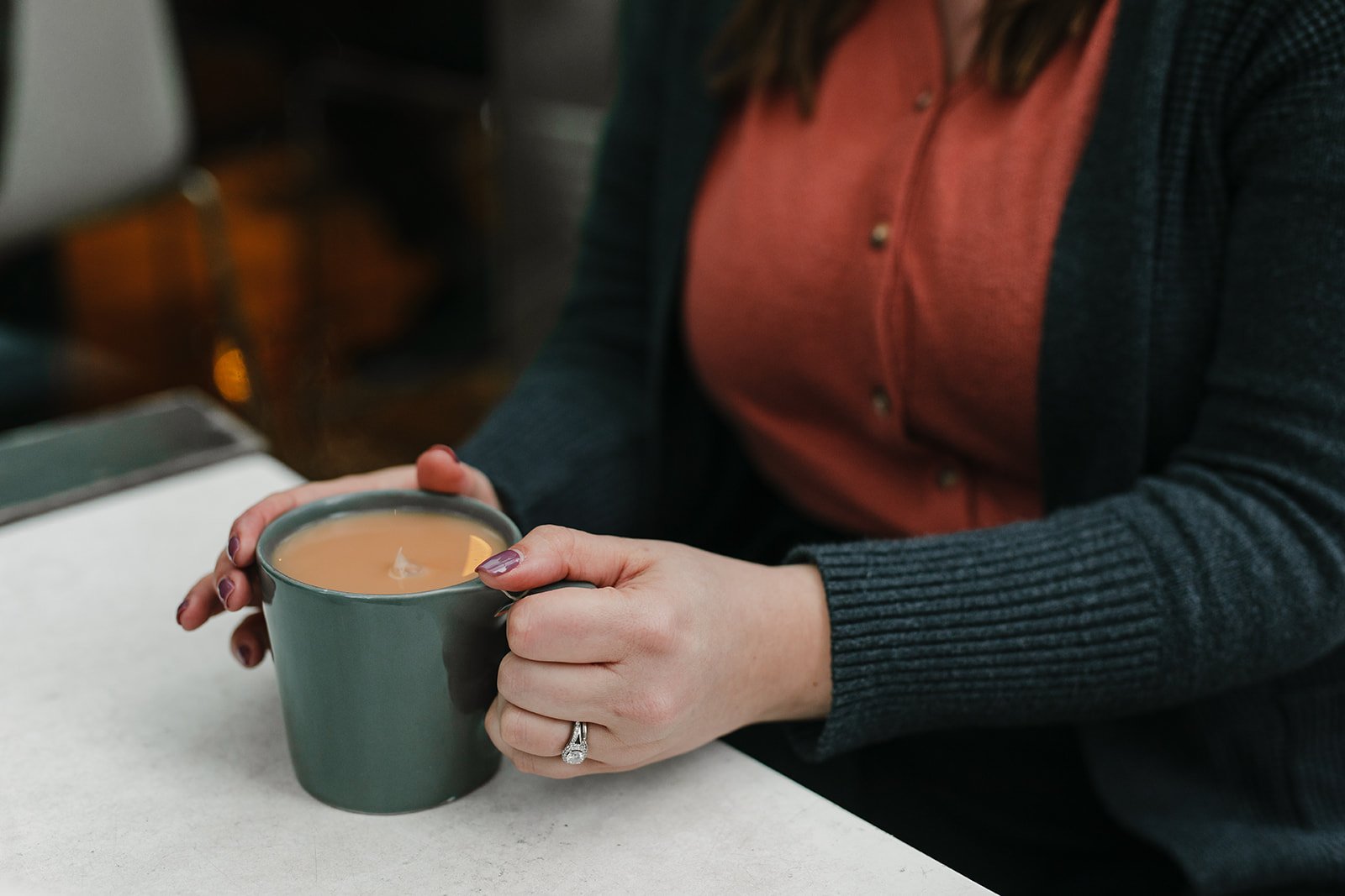 A woman holds a cup of tea.