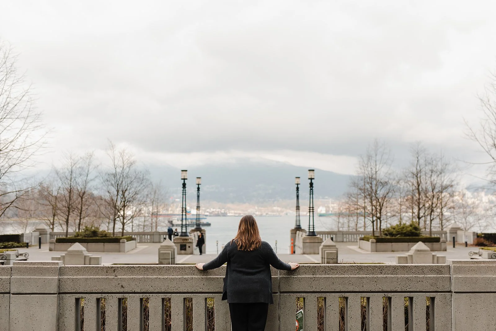 Woman stands looking out over the water.
