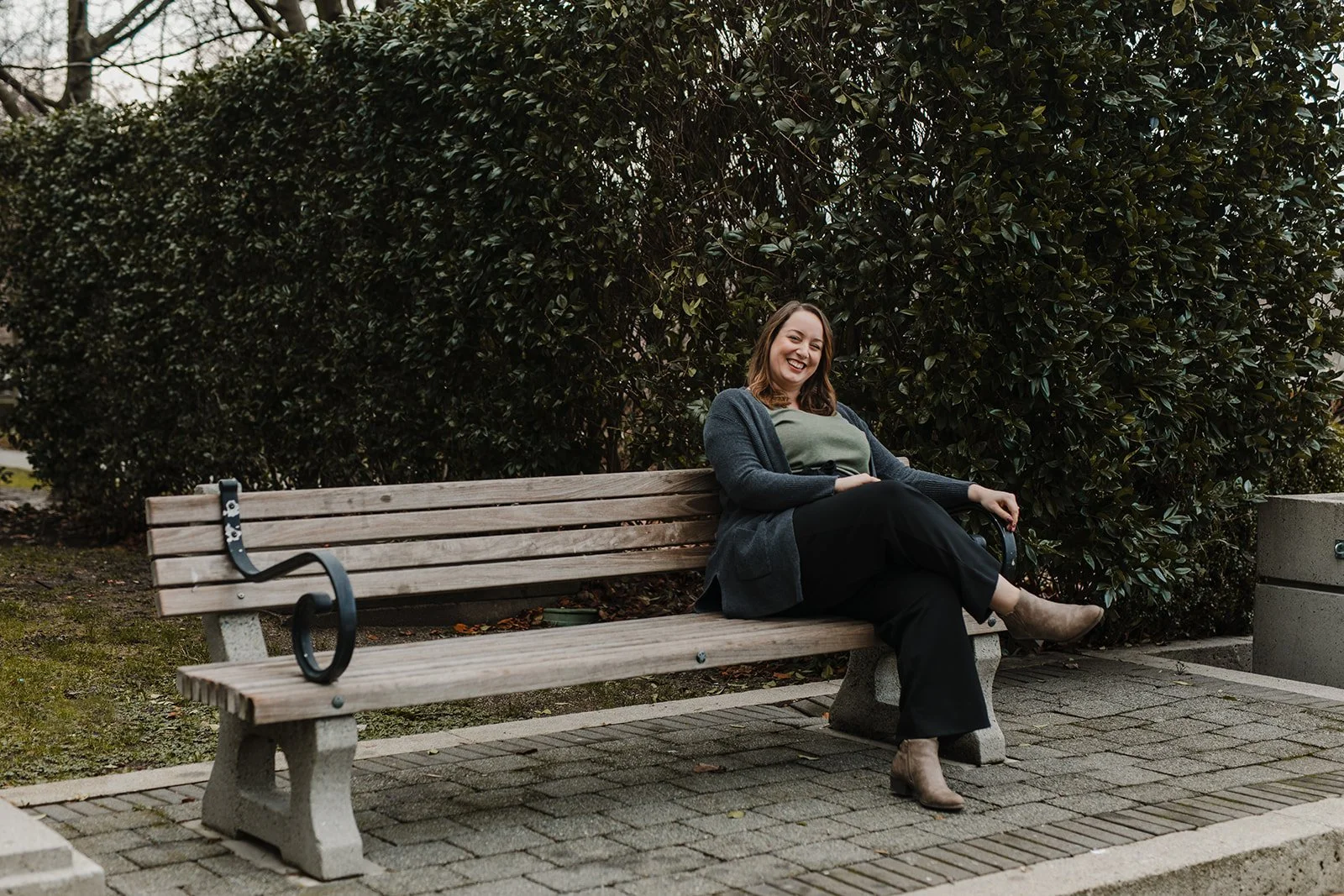 Smiling woman with long, brown hair sitting on a park bench.