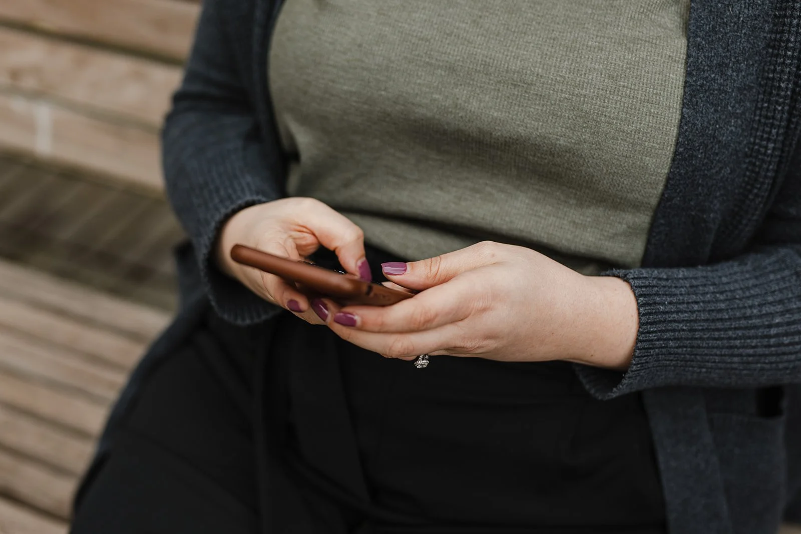 A woman's hands typing on a smart phone.