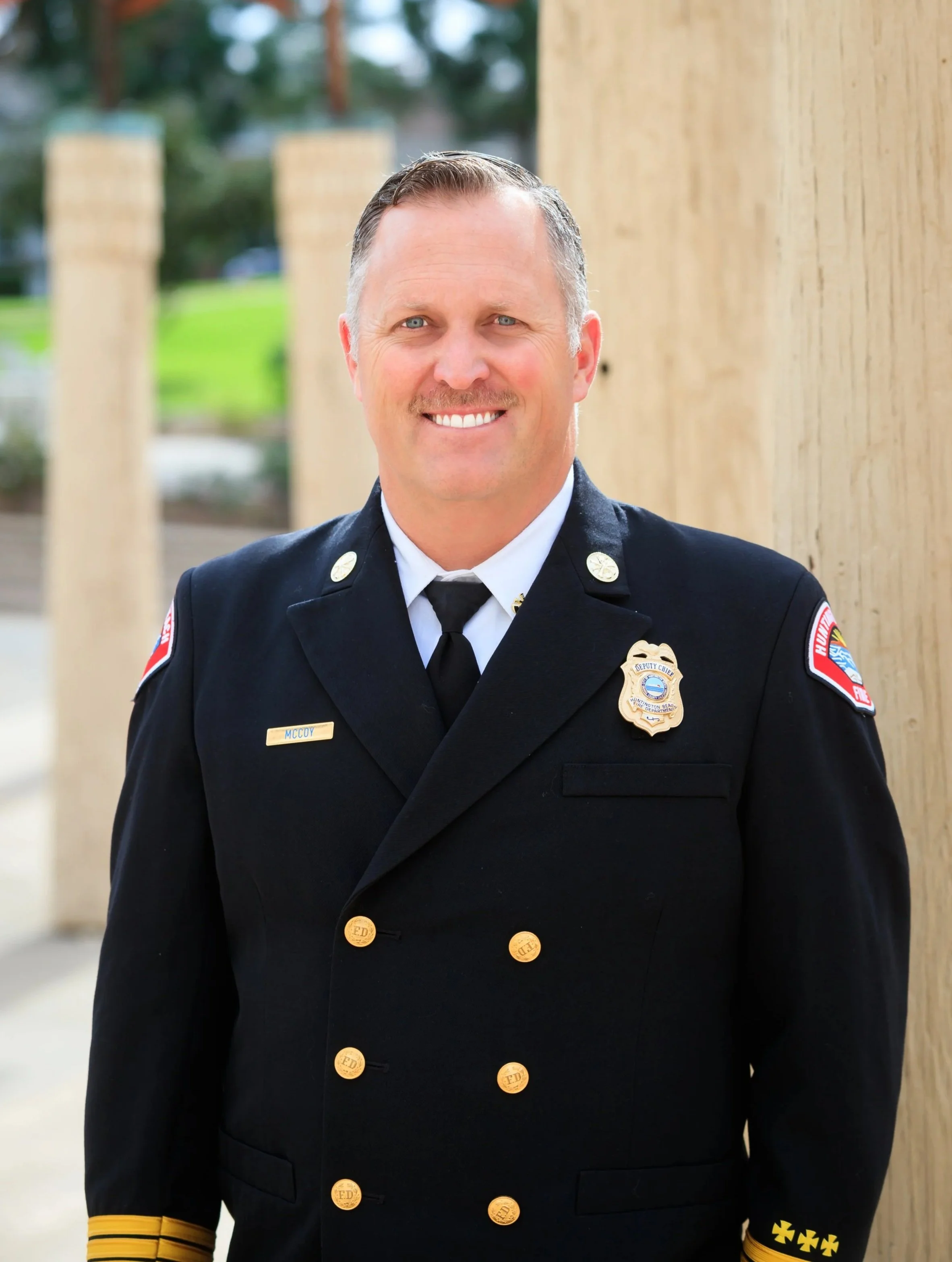 Huntington Beach Fire Chief McCoy standing in front of a pillar in his Class A uniform at City Hall