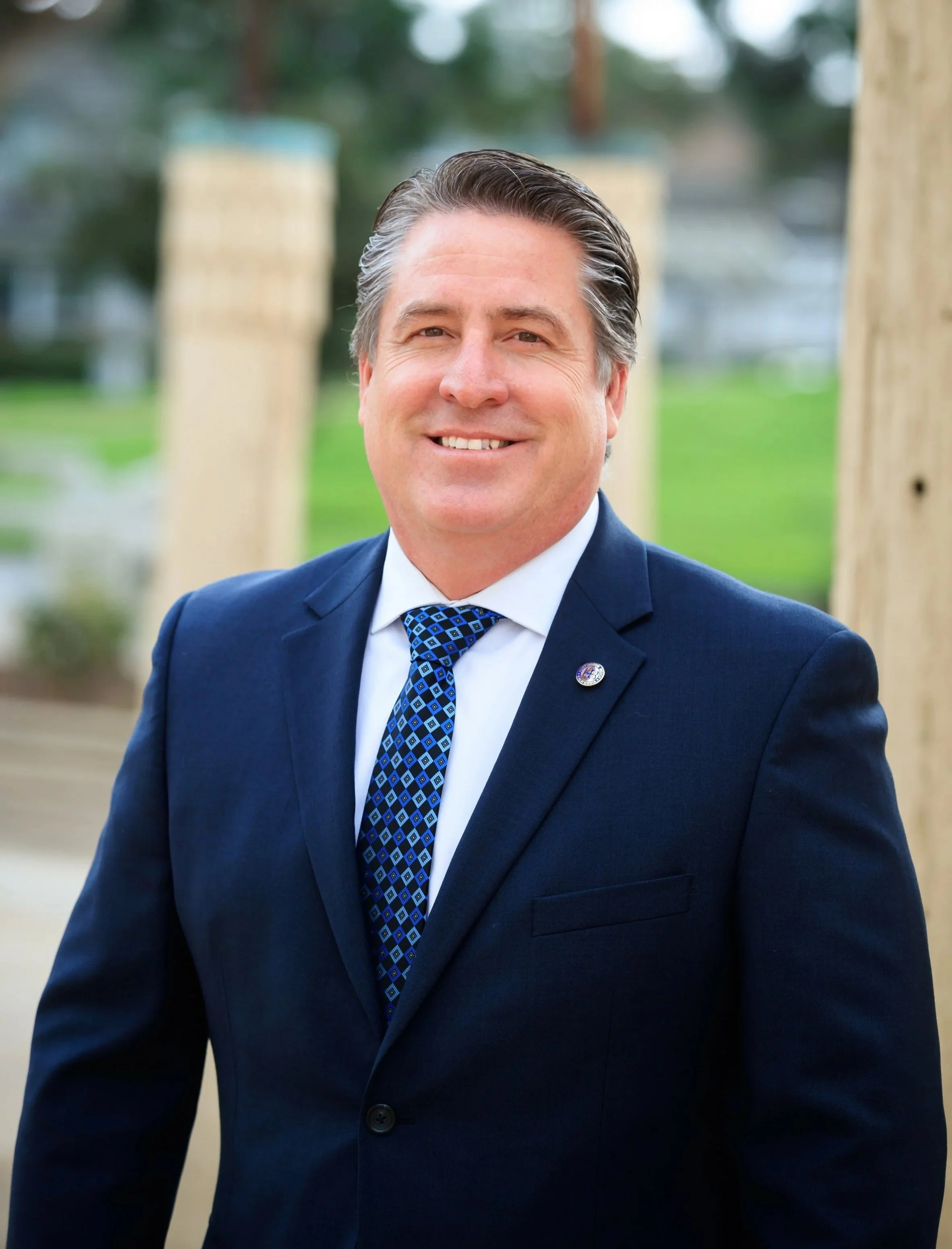 Huntington Beach City Manager Travis Hopkins standing in front of a pillar in a blue suit and tie at City Hall