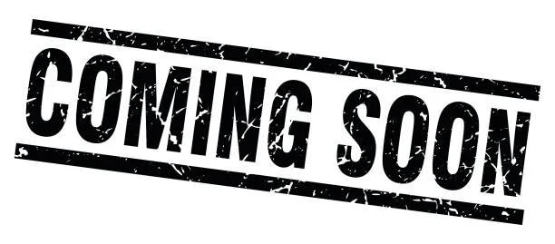 A man with short dark hair, glasses, and a beard and mustache wearing a white shirt and a dark tie, standing against a plain gray background.