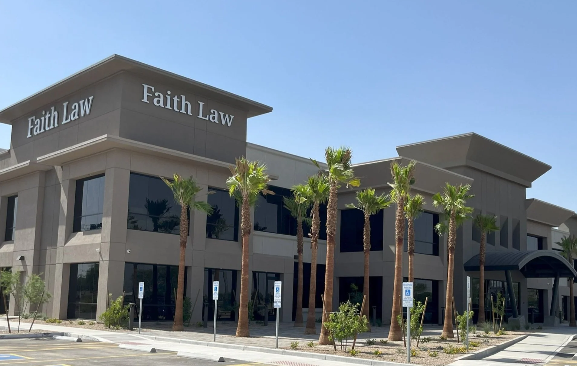 Modern two-story building with signs that read 'Faith Law', surrounded by palm trees and parking spaces, in a sunny location.