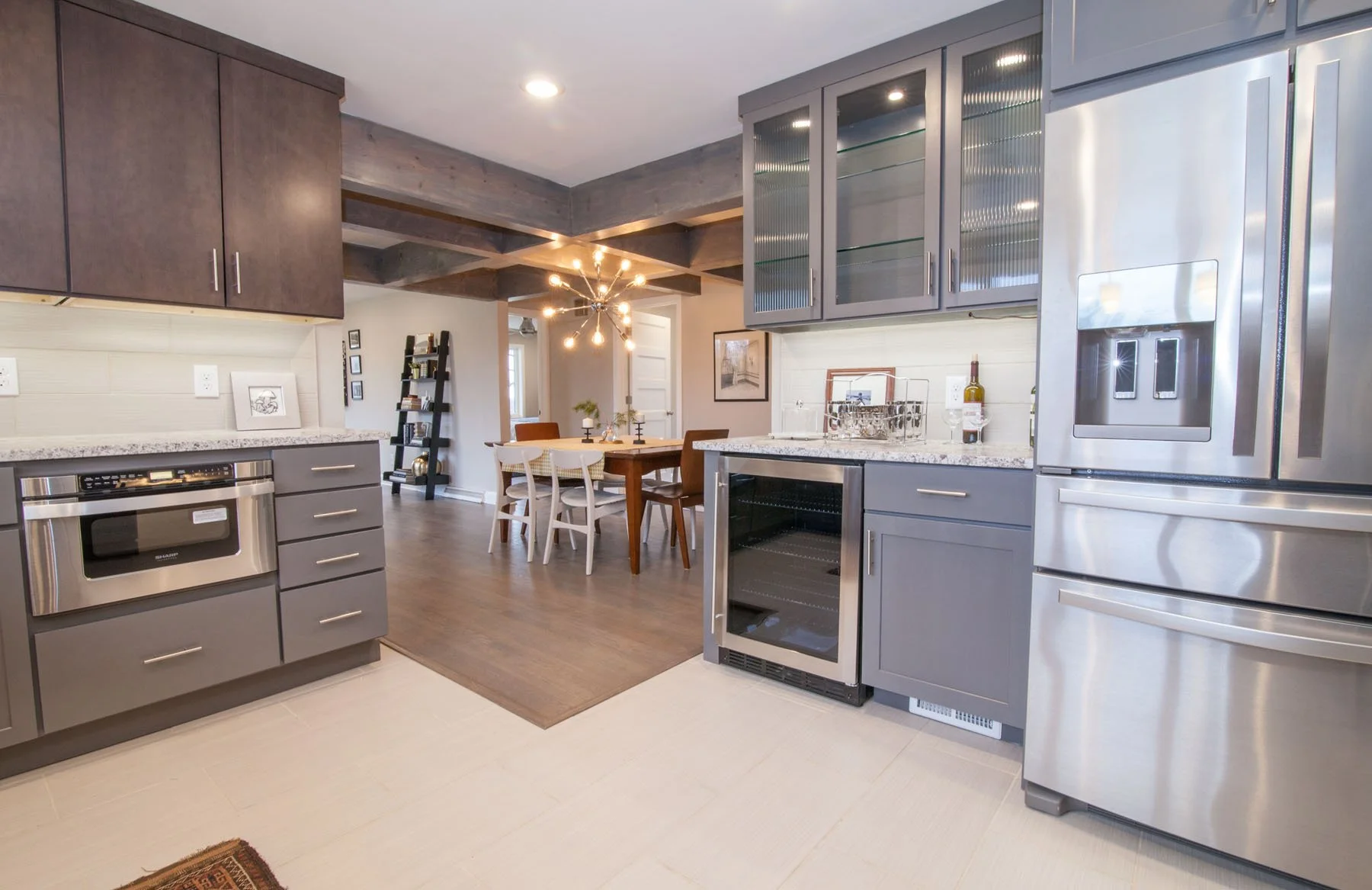 Modern Harford County kitchen remodel with stainless appliances, gray cabinets, and open dining space highlighted by a starburst chandelier
