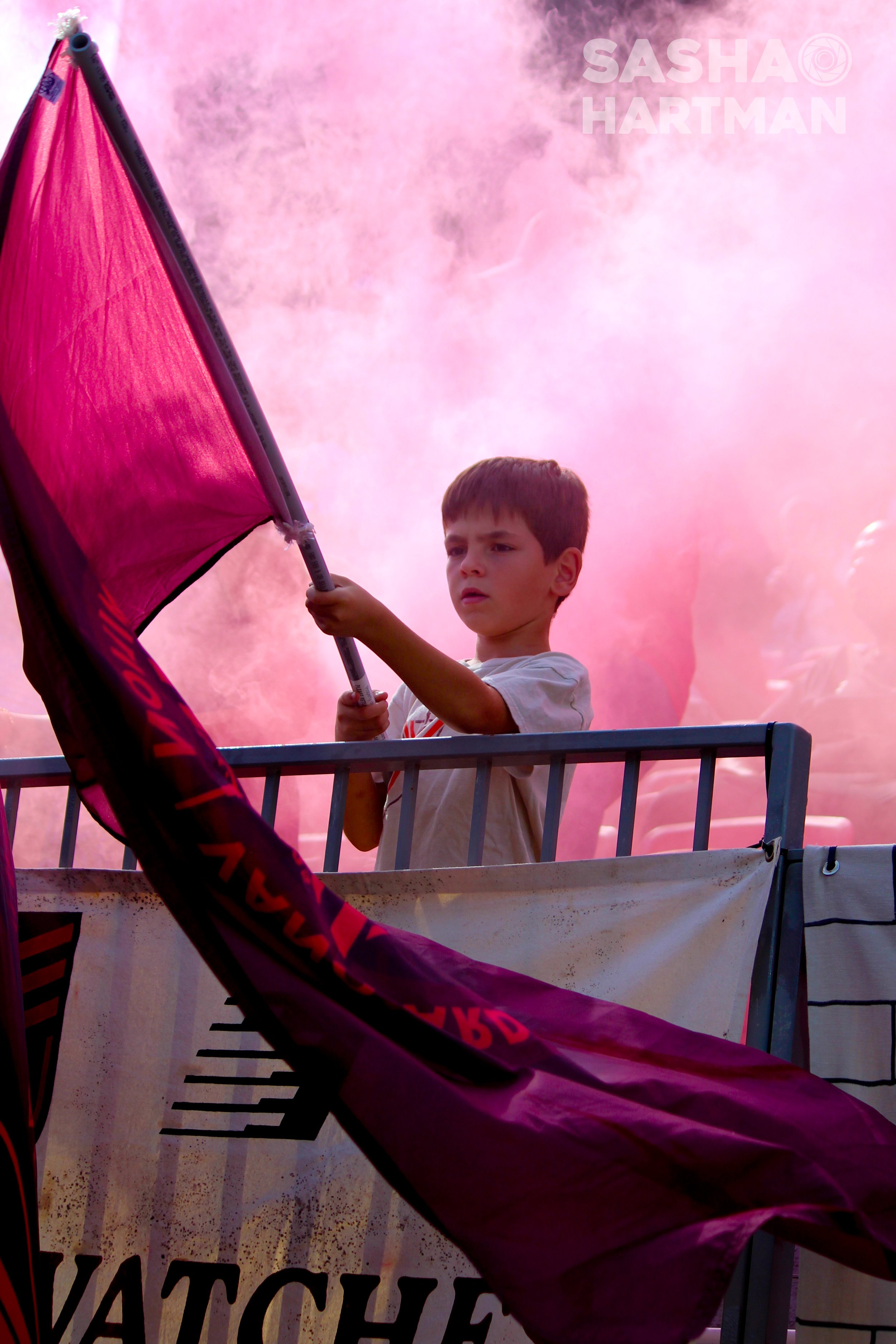 Young boy holding a red flag, with red smoke in the background.