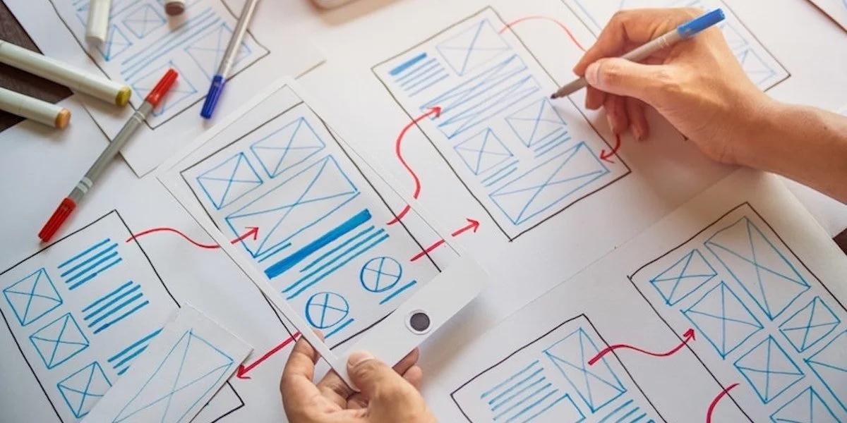 People working on website wireframe sketches with marked layouts and design elements.