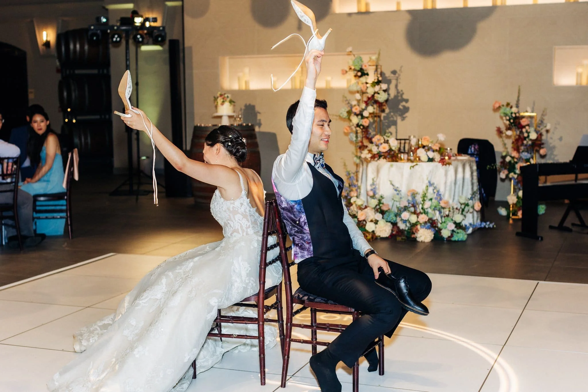 bride and groom sitting back to back holding up shoes wedding reception game palm event center pleasanton